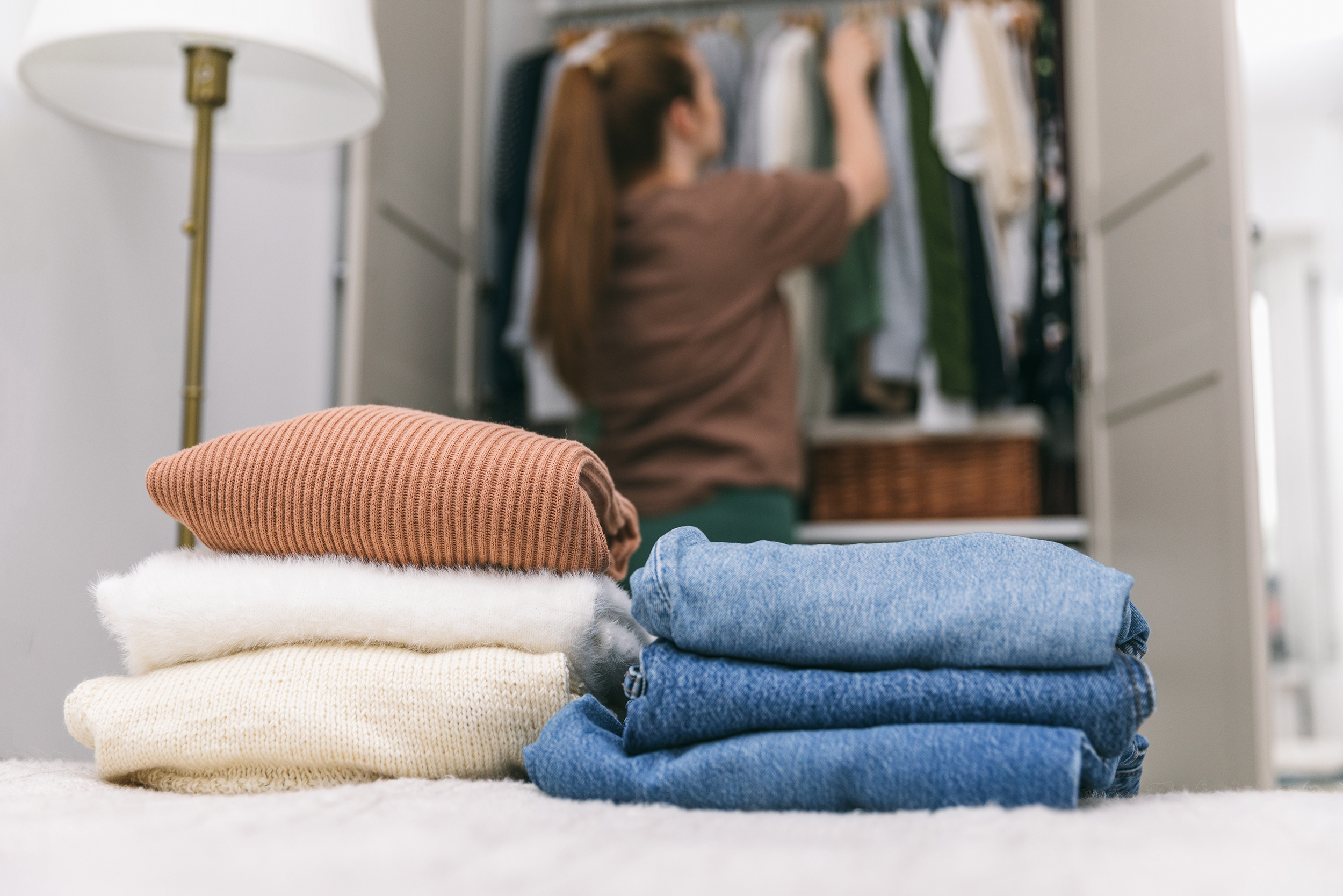A,Woman,Is,Cleaning,Out,Her,Wardrobe,,Standing,By,Clothes