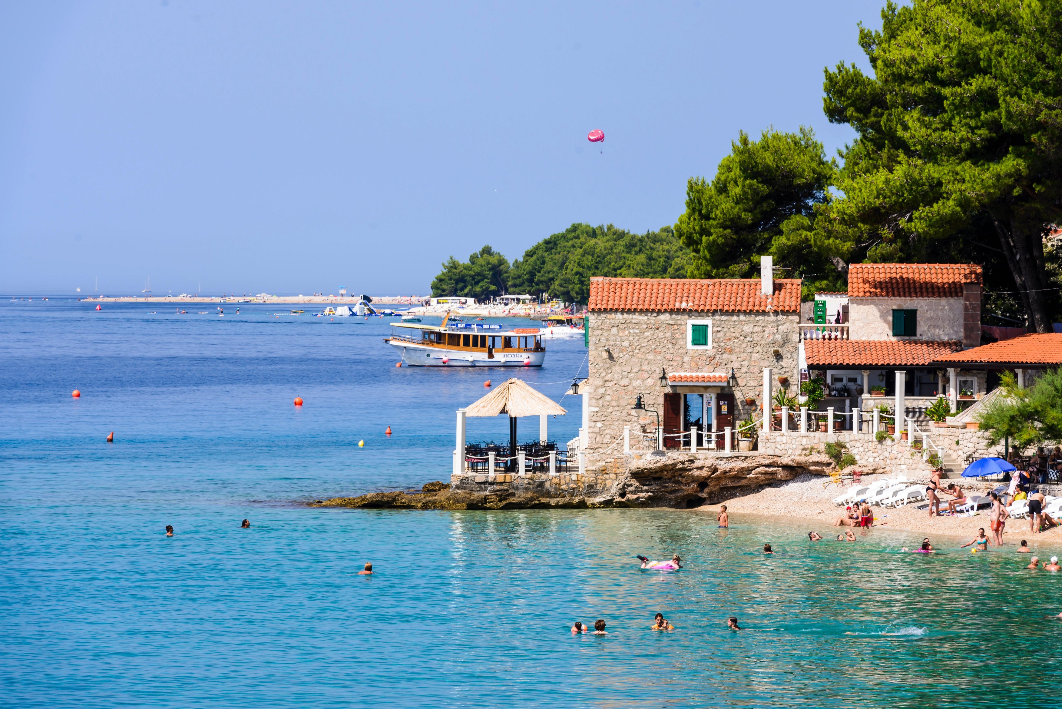 Bol, Croatia - July 7 2016: Beach bar &amp; Restaurant Ribarska kucica in Bol, island of Brac. Famous beach Zlatni rat in background