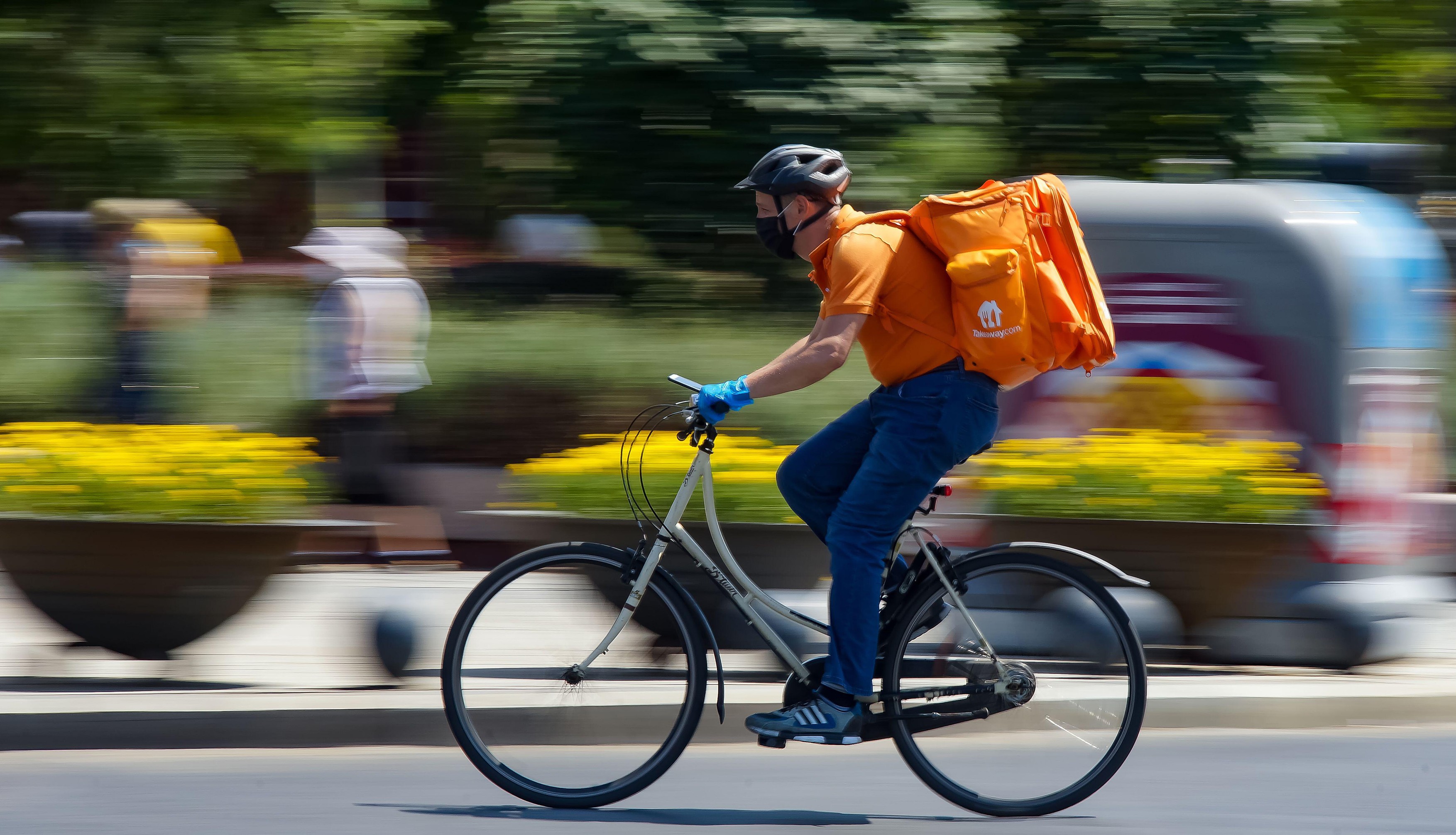 Bucharest, Romania - August 04, 2020: A Takeaway food delivery courier on a bike in high speed in heavy traffic on a boulevard in Bucharest.
