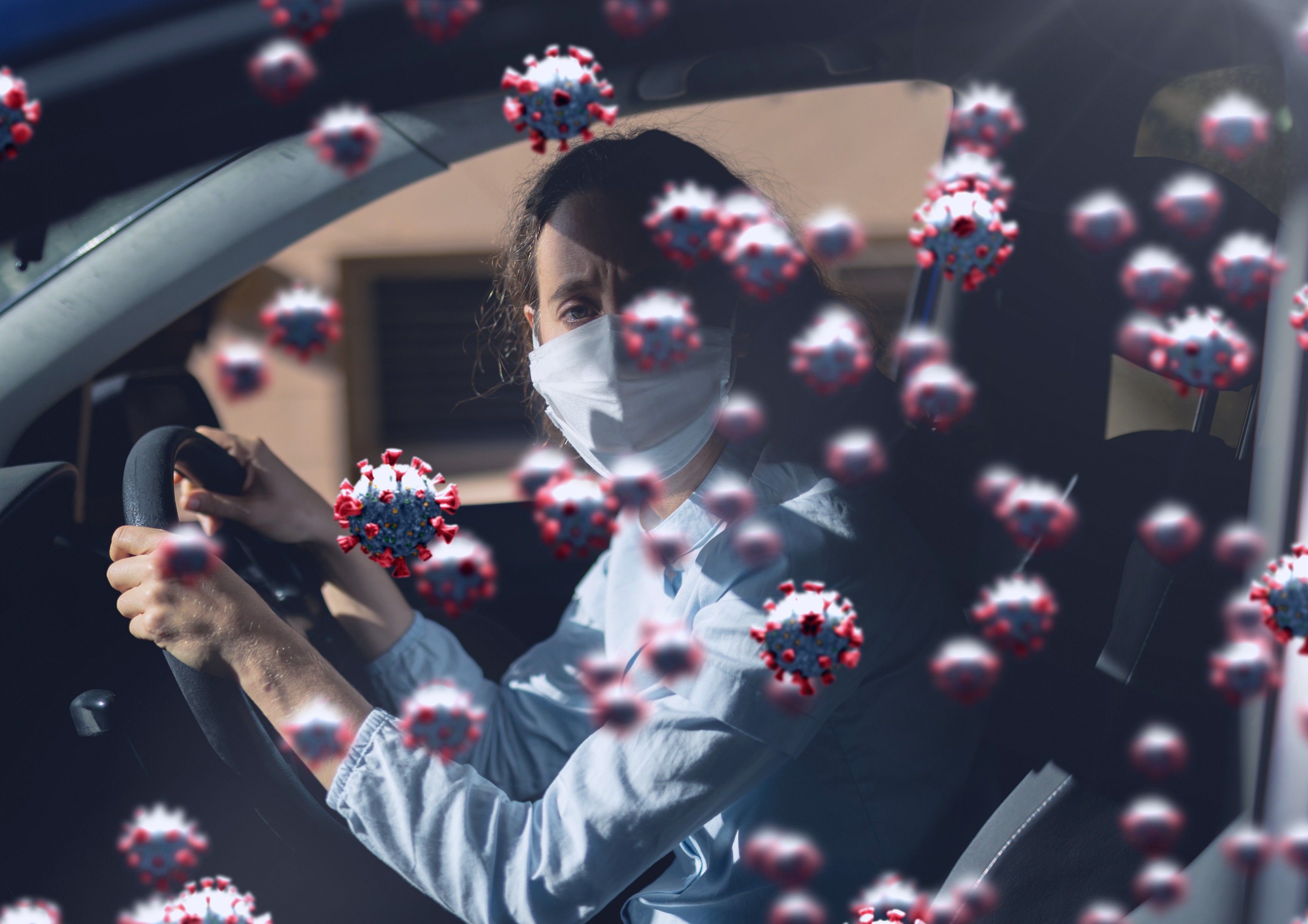 Multiple covid-19 cells against portrait of caucasian woman wearing face mask driving a car