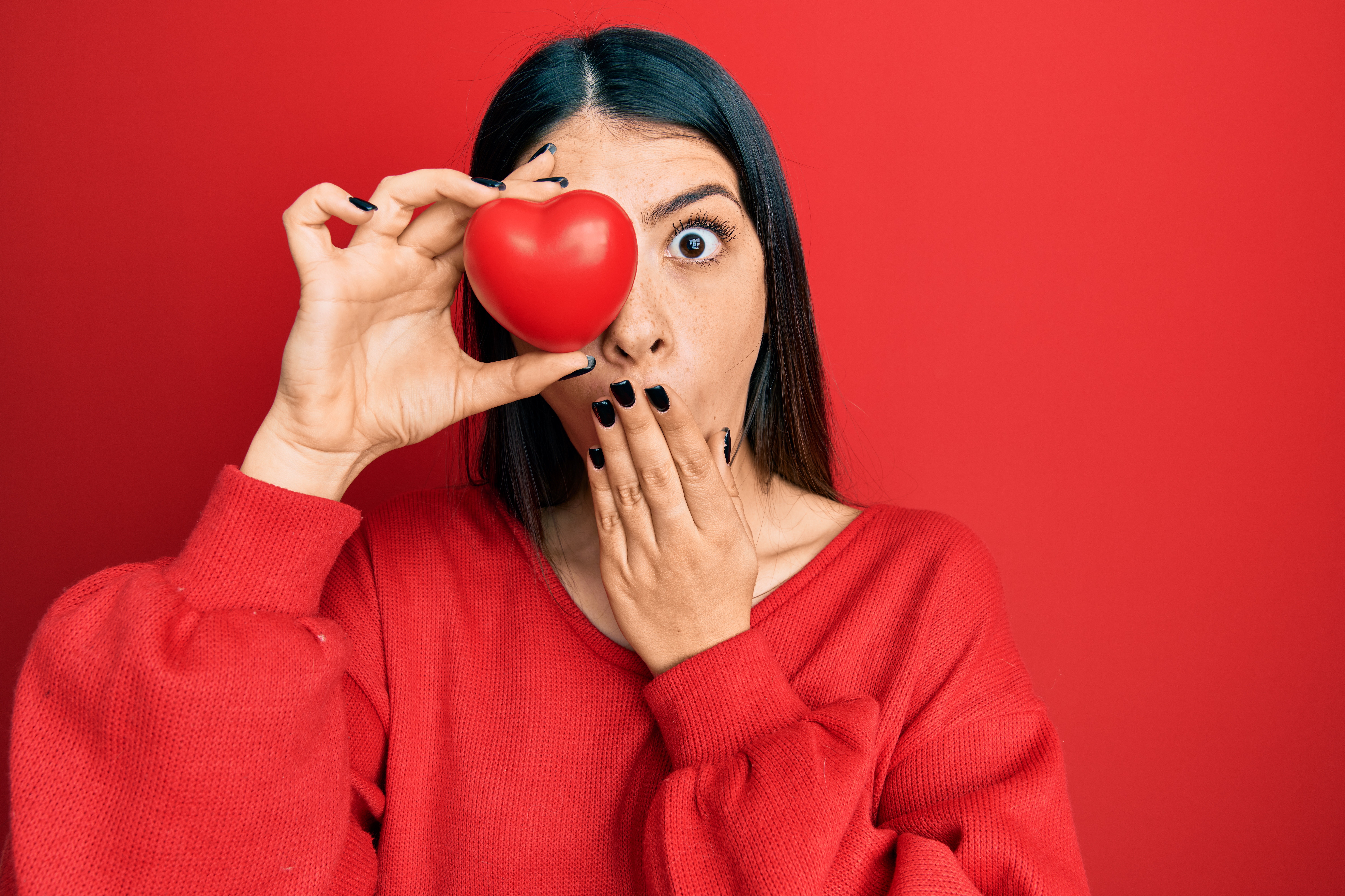 Young,Hispanic,Woman,Holding,Heart,Over,Eye,Covering,Mouth,With