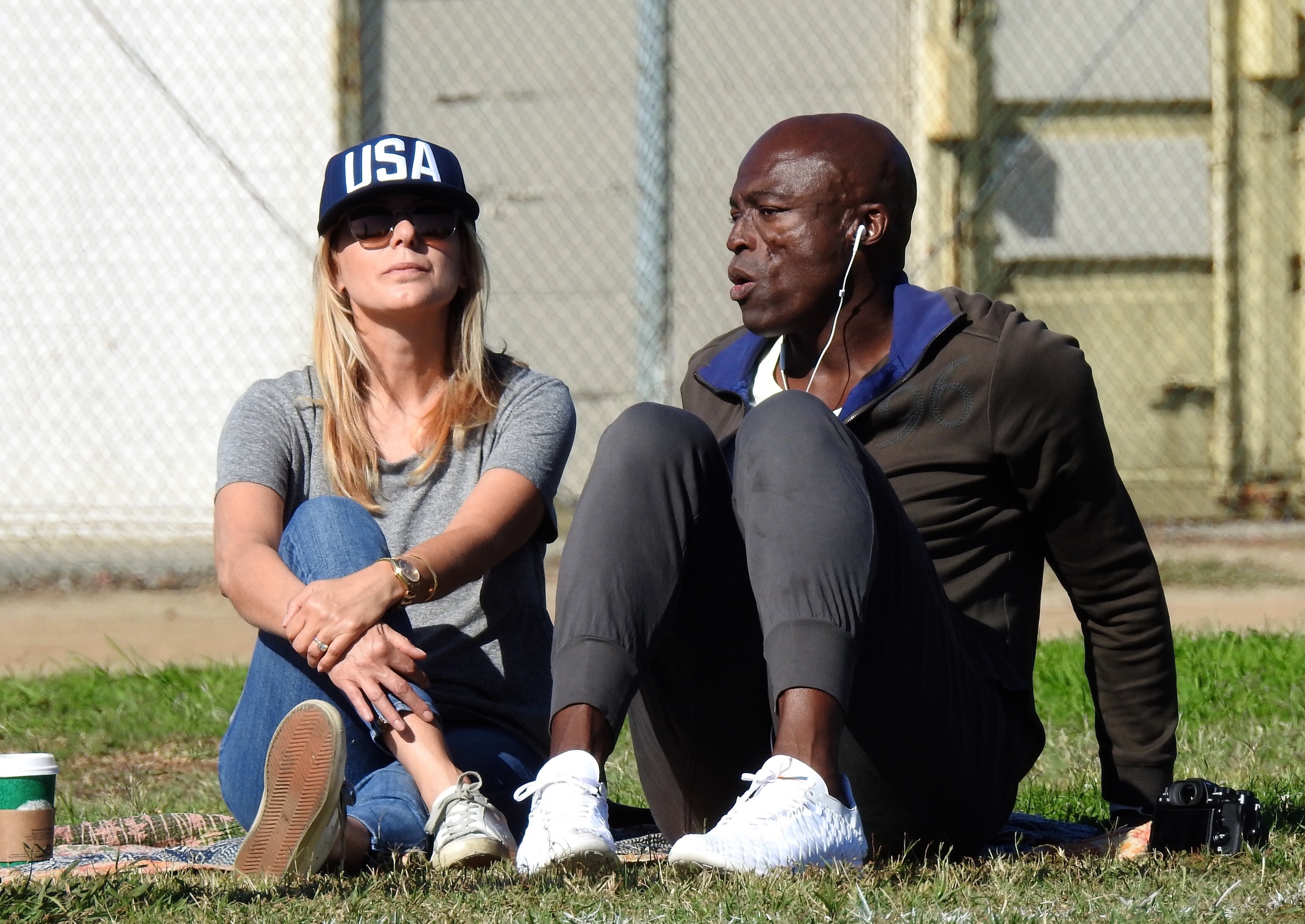 The singer known as 'Seal' sits with a female who resembles his ex-wife Heidi Klum while he watches his son play sports.