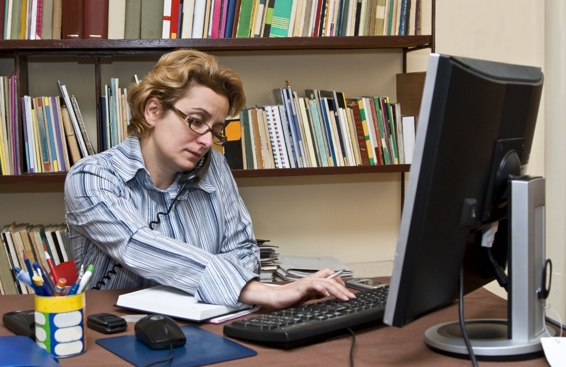 Busy businesswoman at her home business desk.