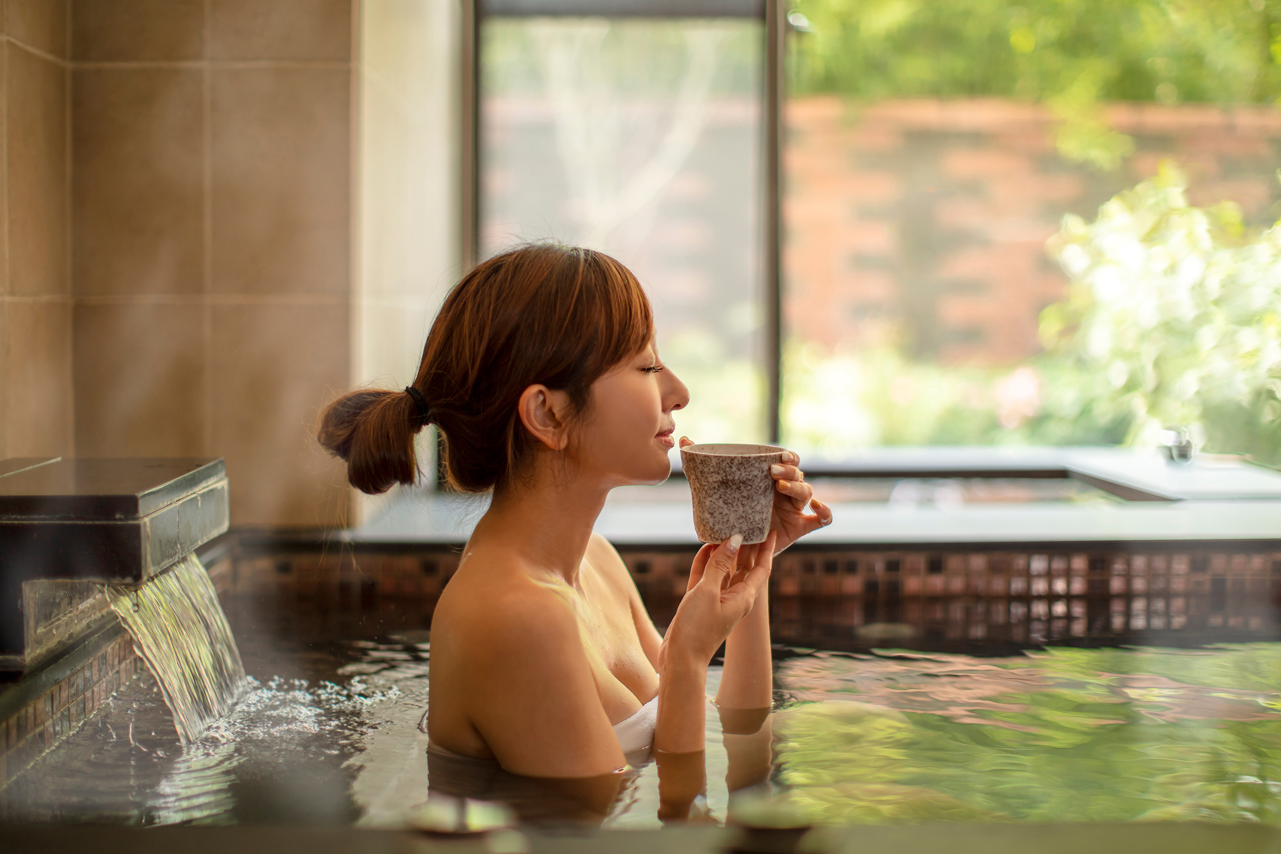 Young,Woman,Relaxing,In,Hot,Spring,And,Drinking,Tea