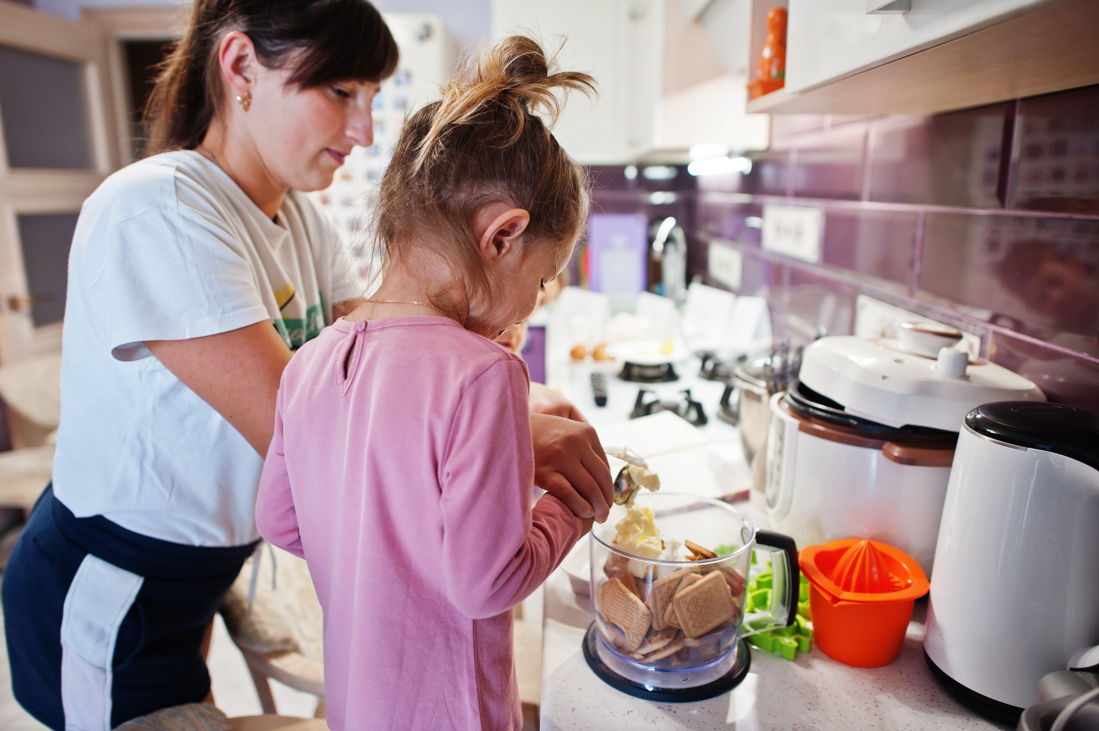 Mother with kids cooking at kitchen, happy children's moments.