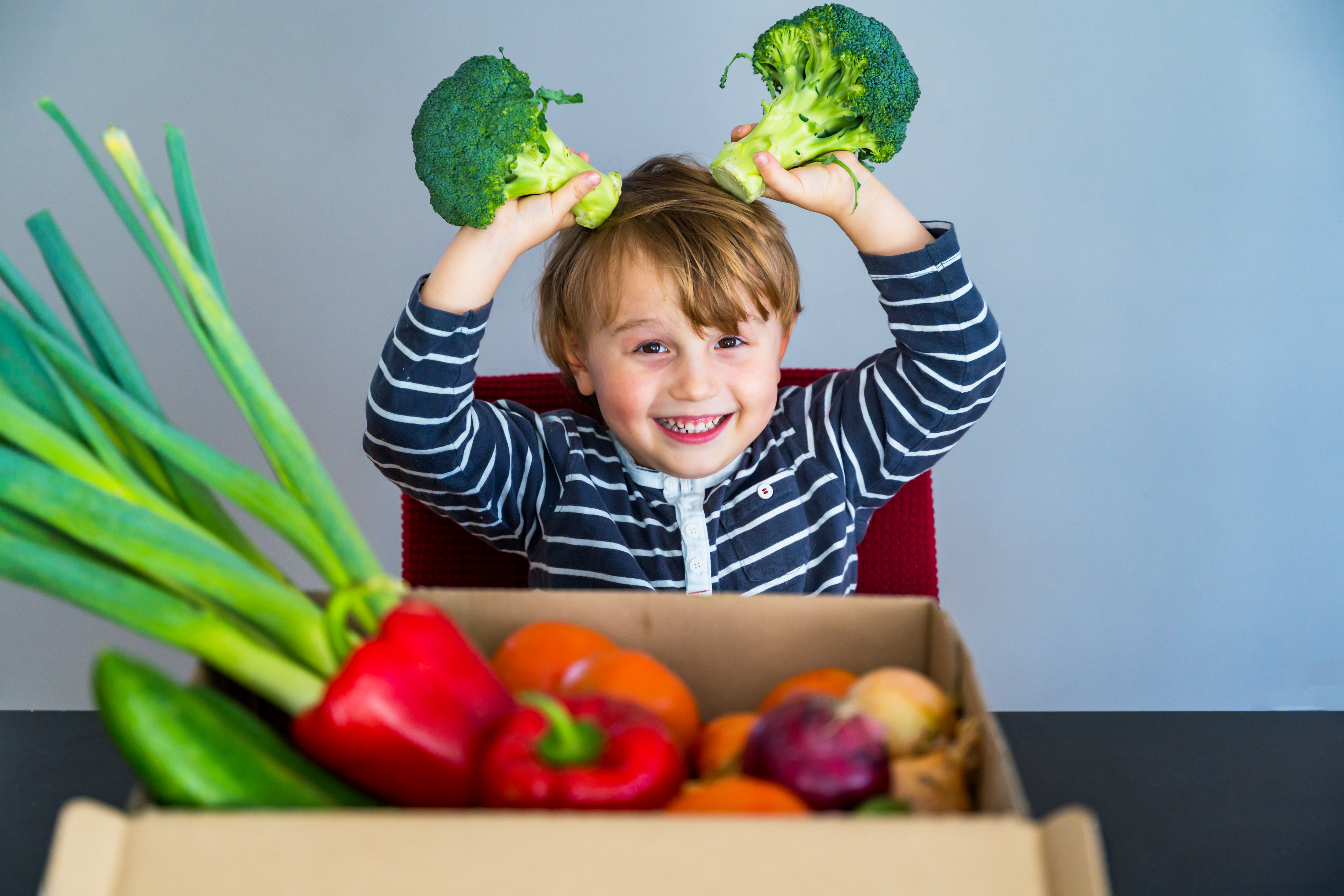 Little,Boy,Sitting,At,The,Table,And,Taking,Broccoli,In