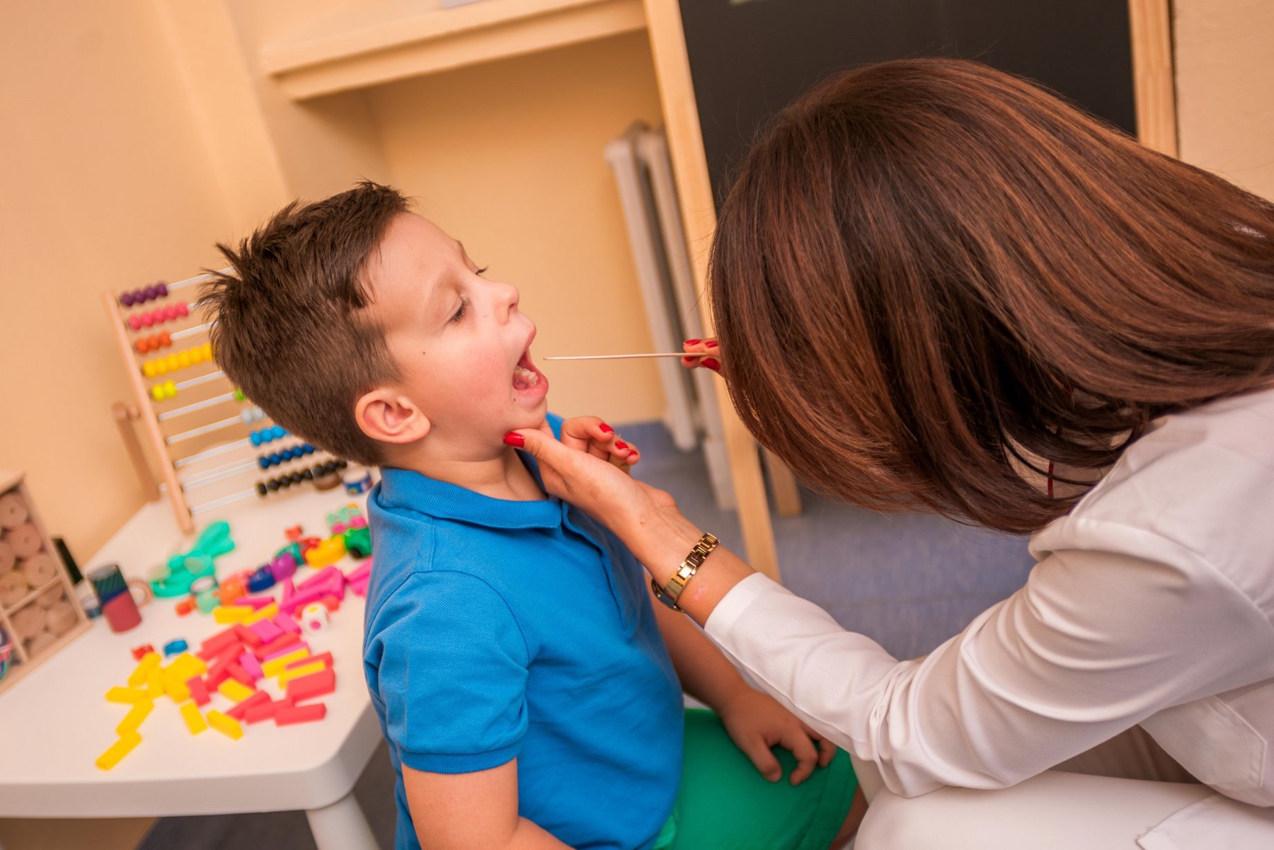Female Pediatrician check's the throat and mouth of a young cute boy.