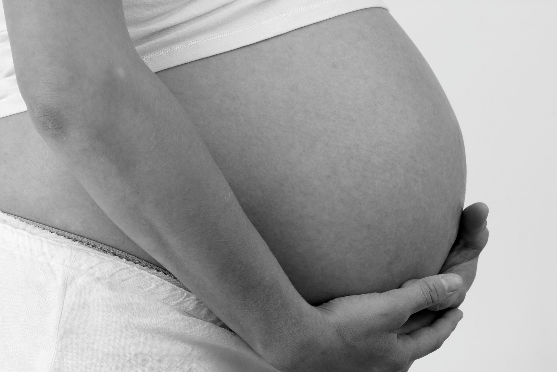 Side view cropped shot of a heavily pregnant woman with hands around stomach