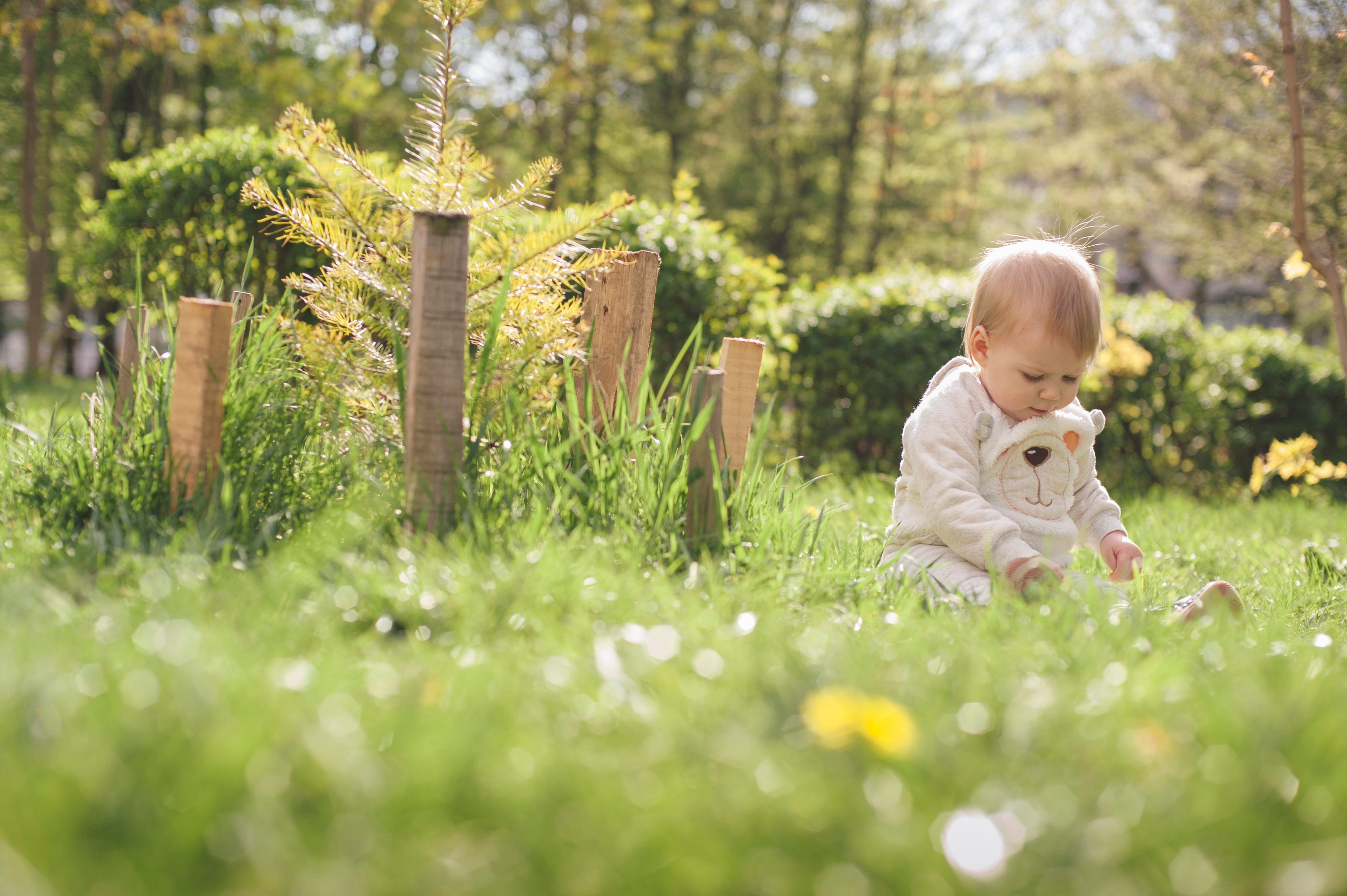 Little,Baby,Sitting,On,The,Green,Grass,Near,The,Trees