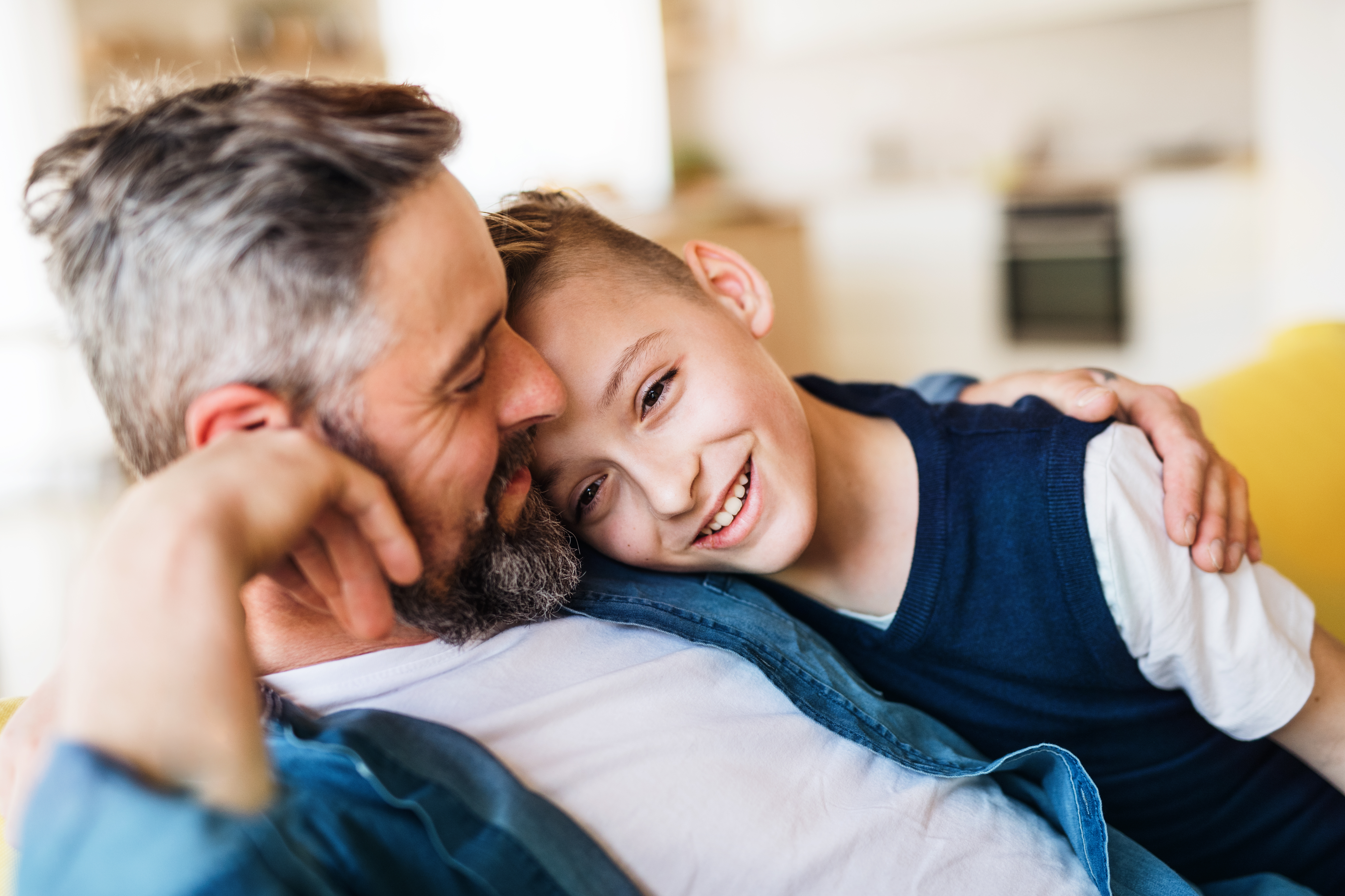 Mature,Father,With,Small,Son,Sitting,On,Sofa,Indoors,,Resting.