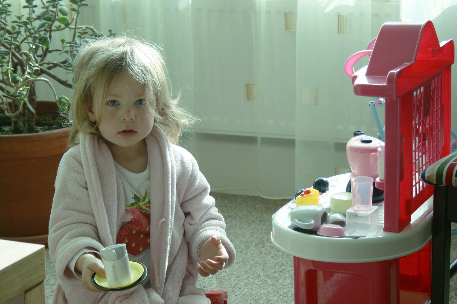 The girl makes coffee in the toy kitchen in the morning.