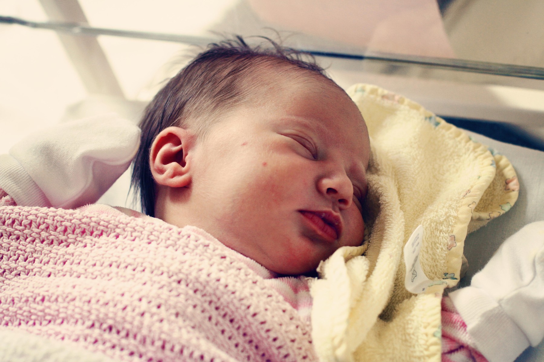 Headshot of newborn baby girl sleeping with black hair