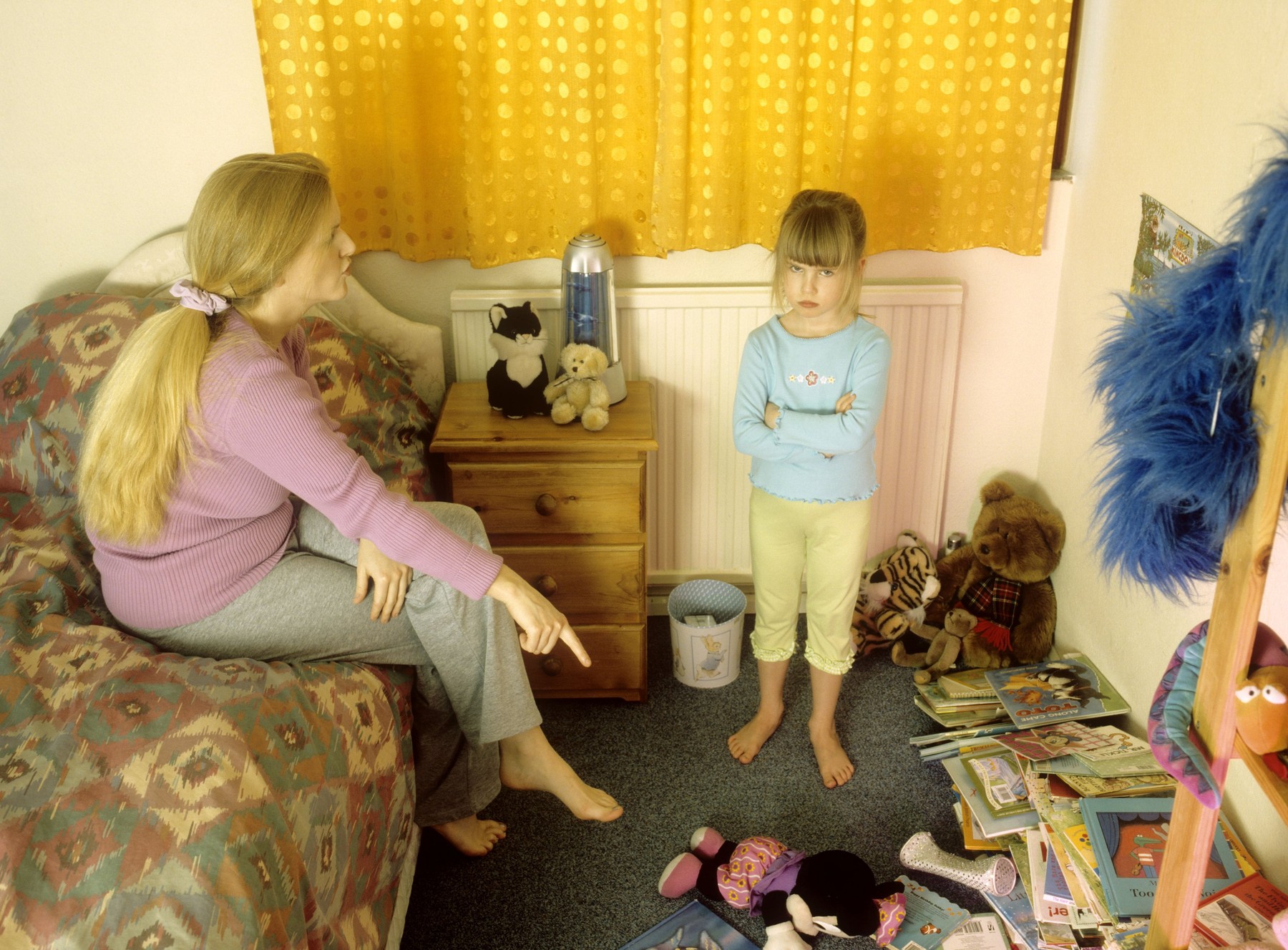 Mother telling off her child in her messy bedroom