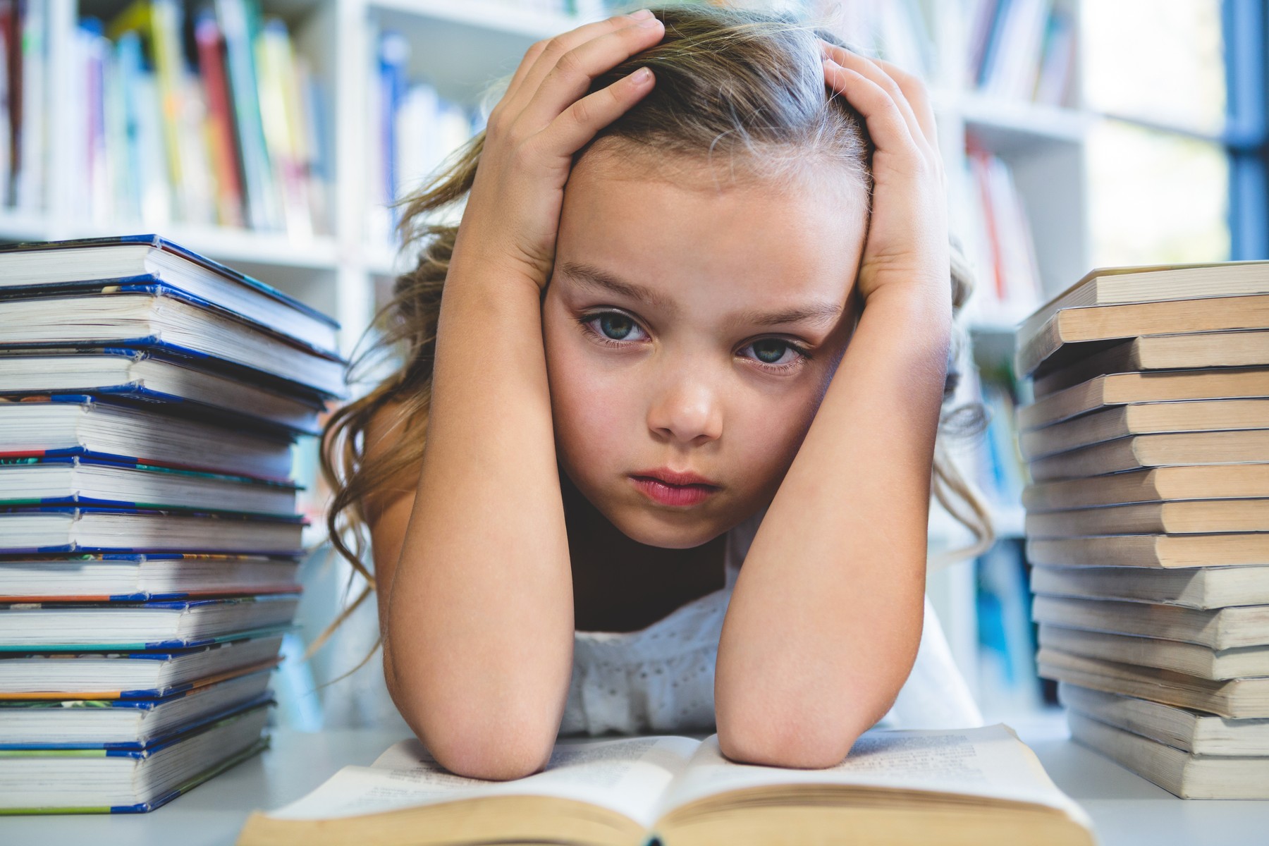 Close-up of stressed girl with head in hand at school library