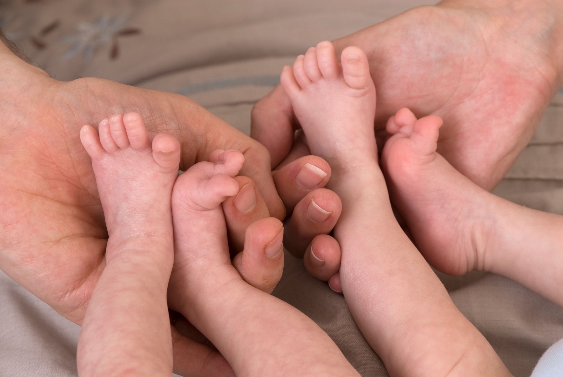 Parents demonstrating containment holding for premature babies, identical twin boys, 11 weeks old, born 10 weeks early