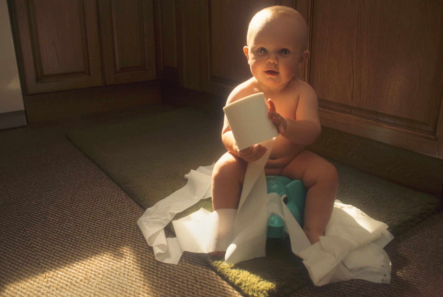 Baby Boy Sitting On His Potty,Amusing Himself By Unwinding A Toilet Roll.
