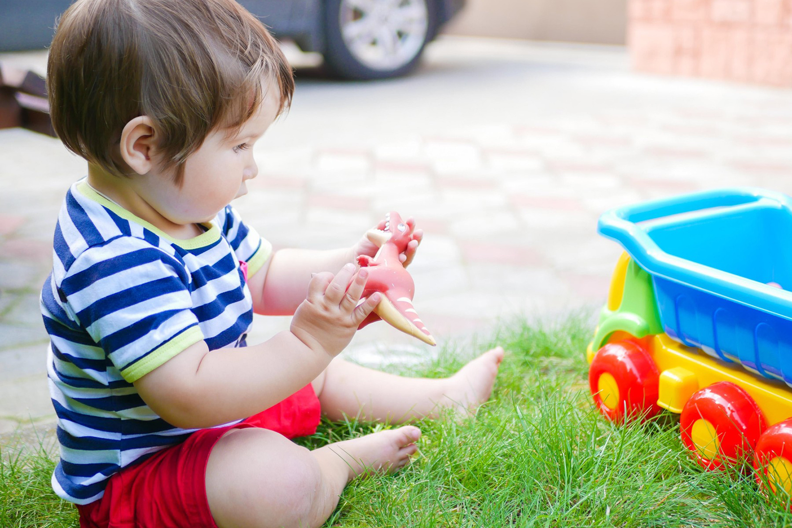 toddler kid having fun playing with a toy dinosaur