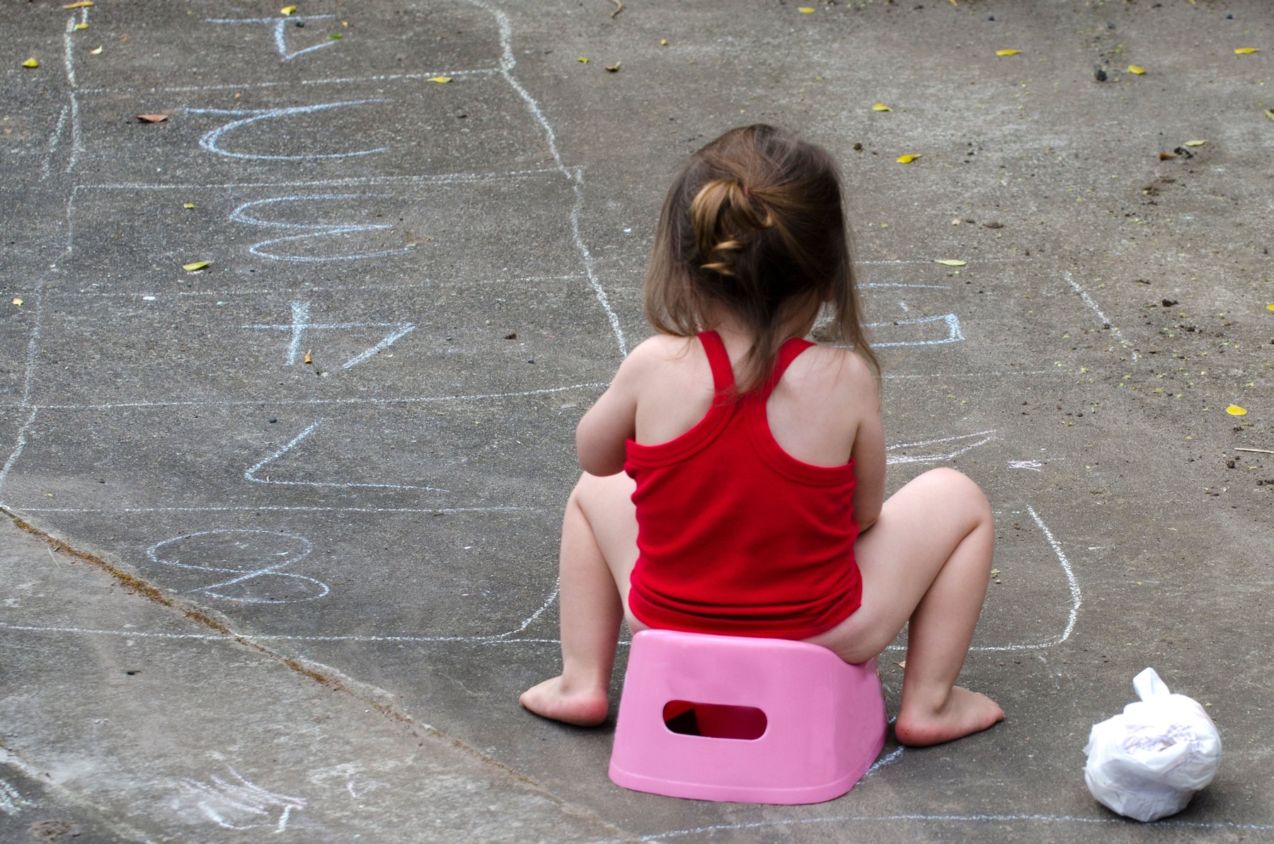 Little baby site on a pink potty outdoor.