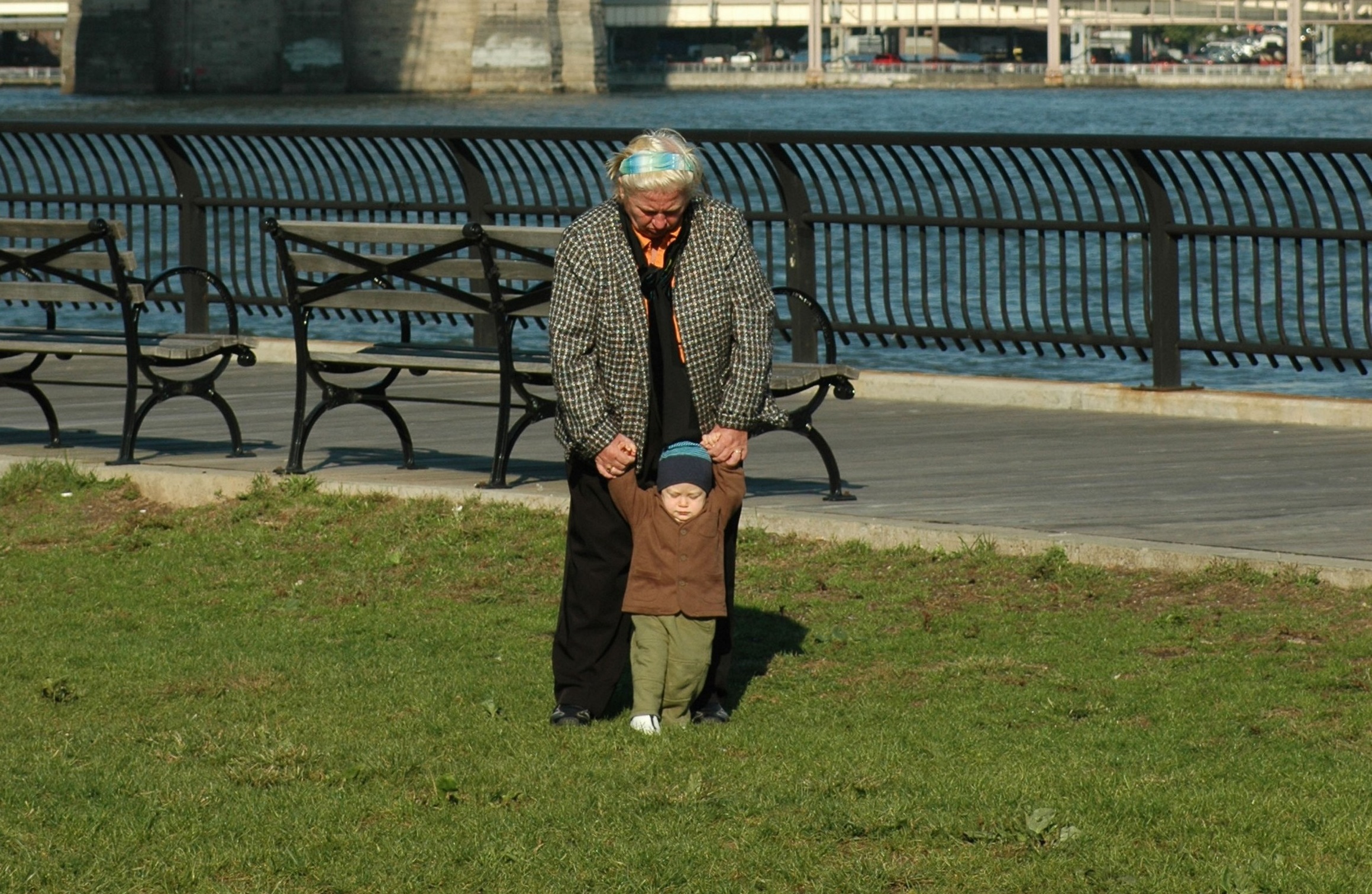 NYC BOY LEARNING TO WALK WITH HIS GRANDMOTHER UNDER THE BROOKLYN BRIDGE FAMILY MORNING MANHATTAN NEW YORK