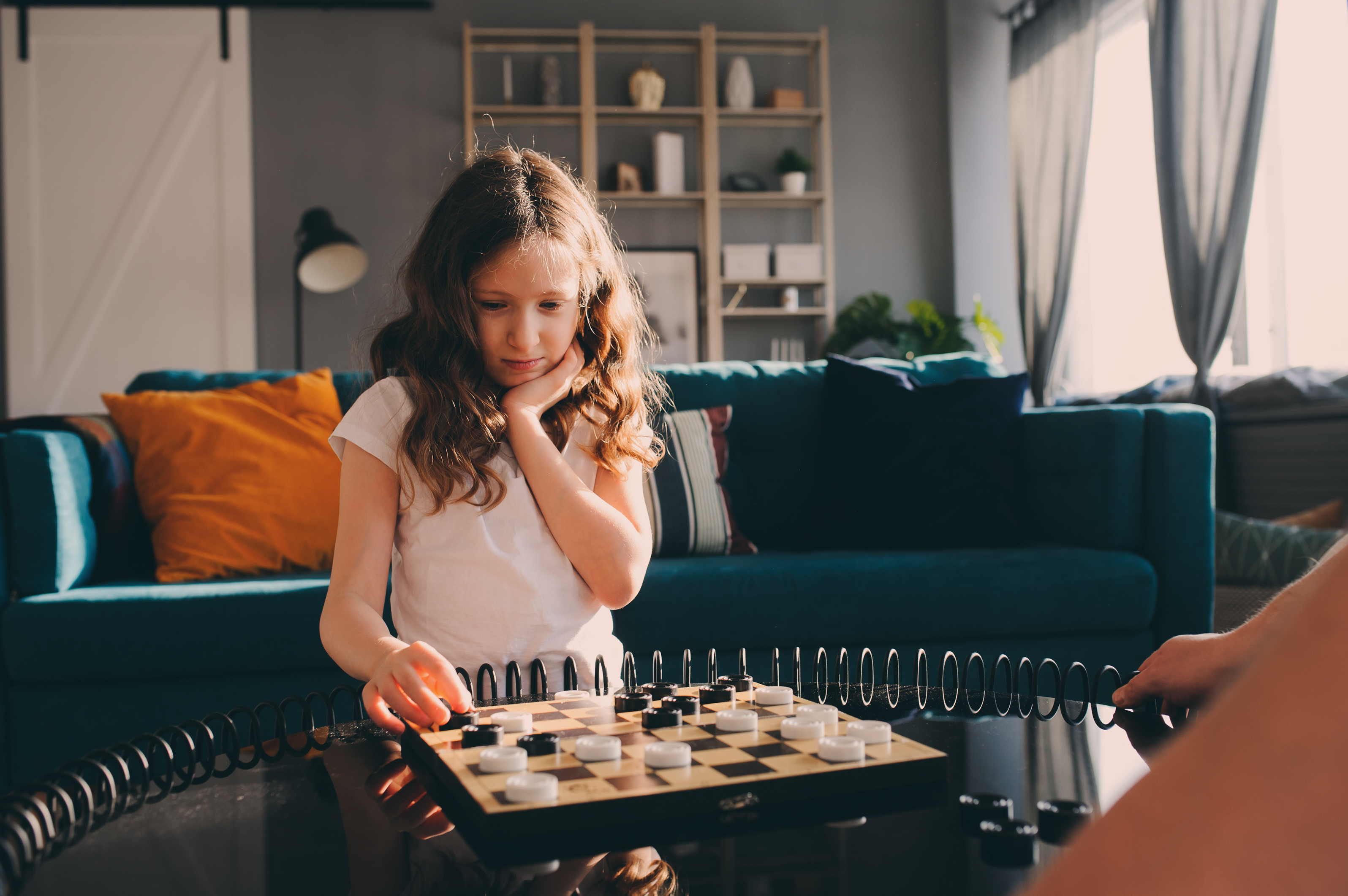 Lifestyle,Shot,Of,Smart,Kid,Girl,Playing,Checkers,At,Home.