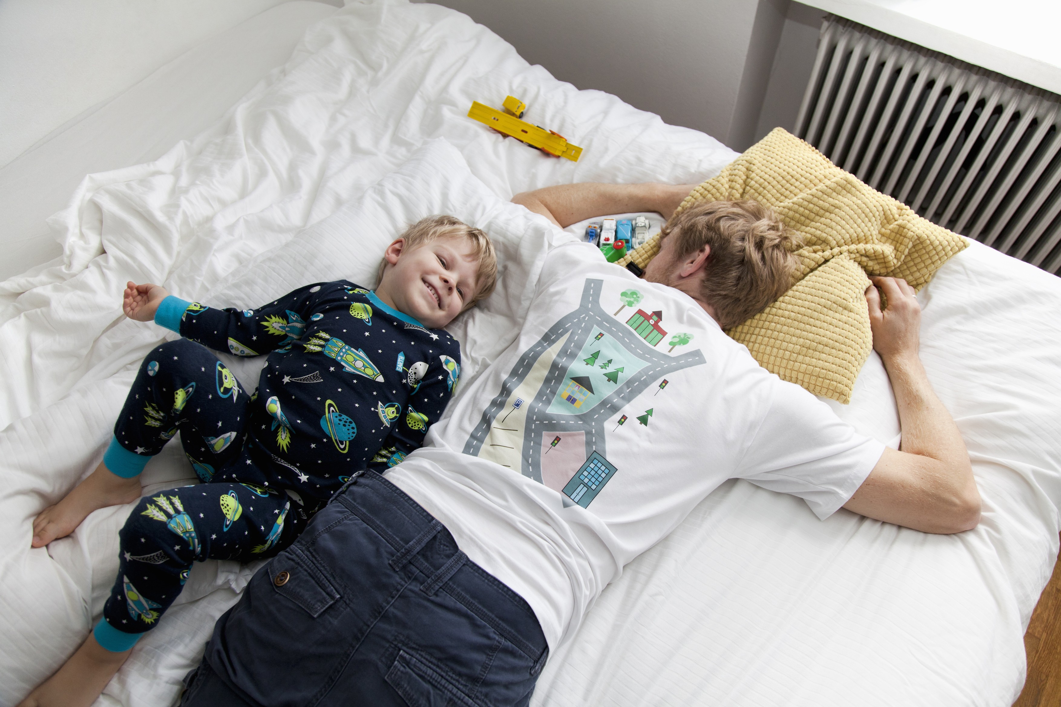 Young boy lying next to father in bed