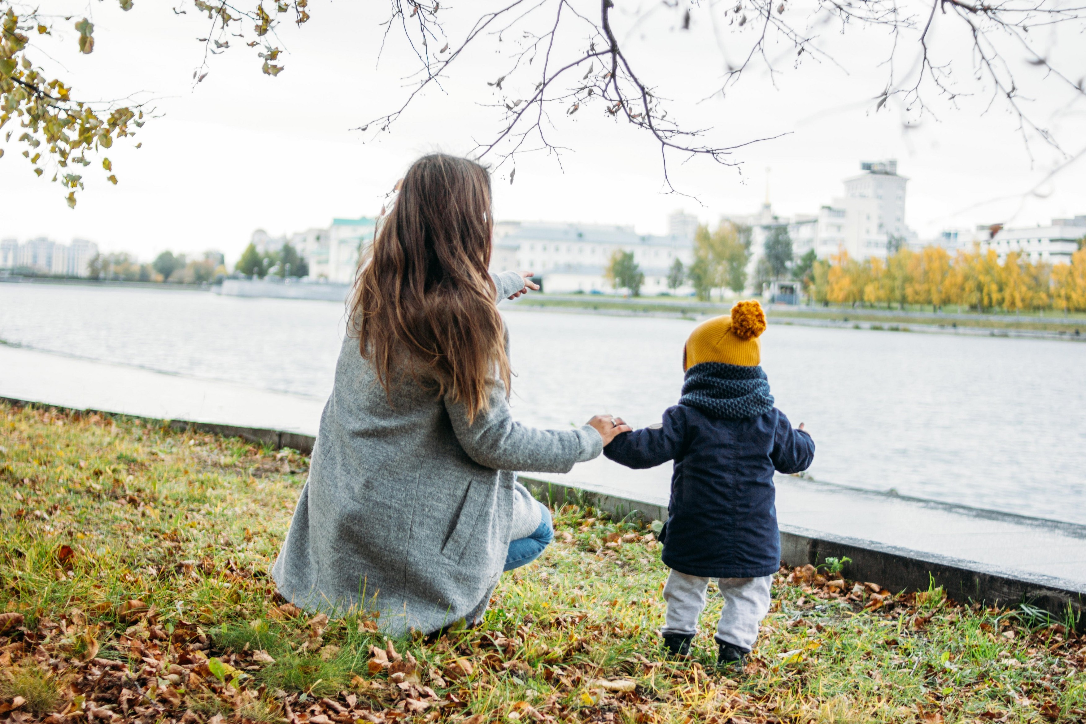 Cute baby boy in fashionable casual clothes explores the world with mother in autumn nature park