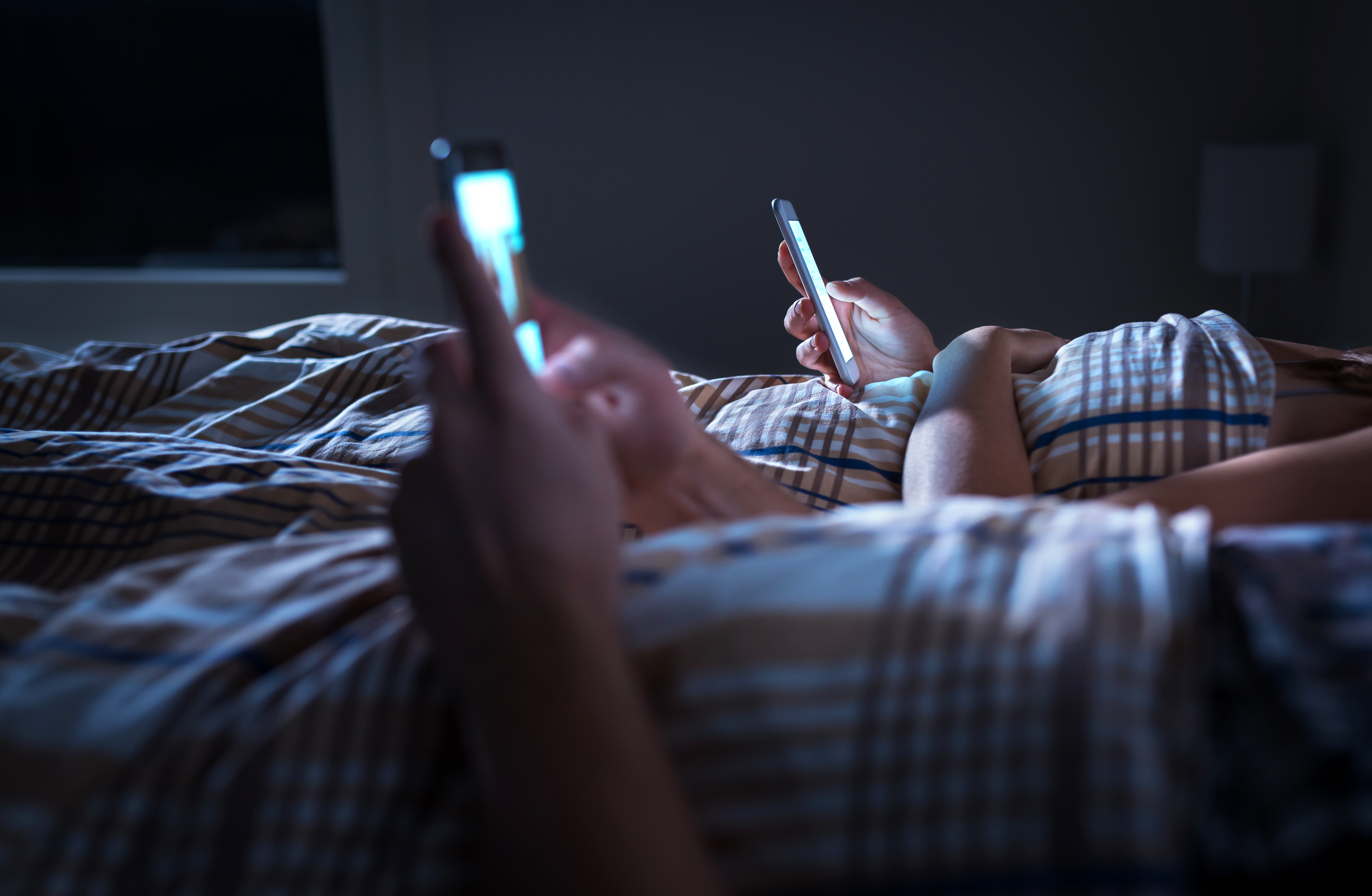 Bored,Distant,Couple,Ignoring,Each,Other,Lying,In,Bed,At
