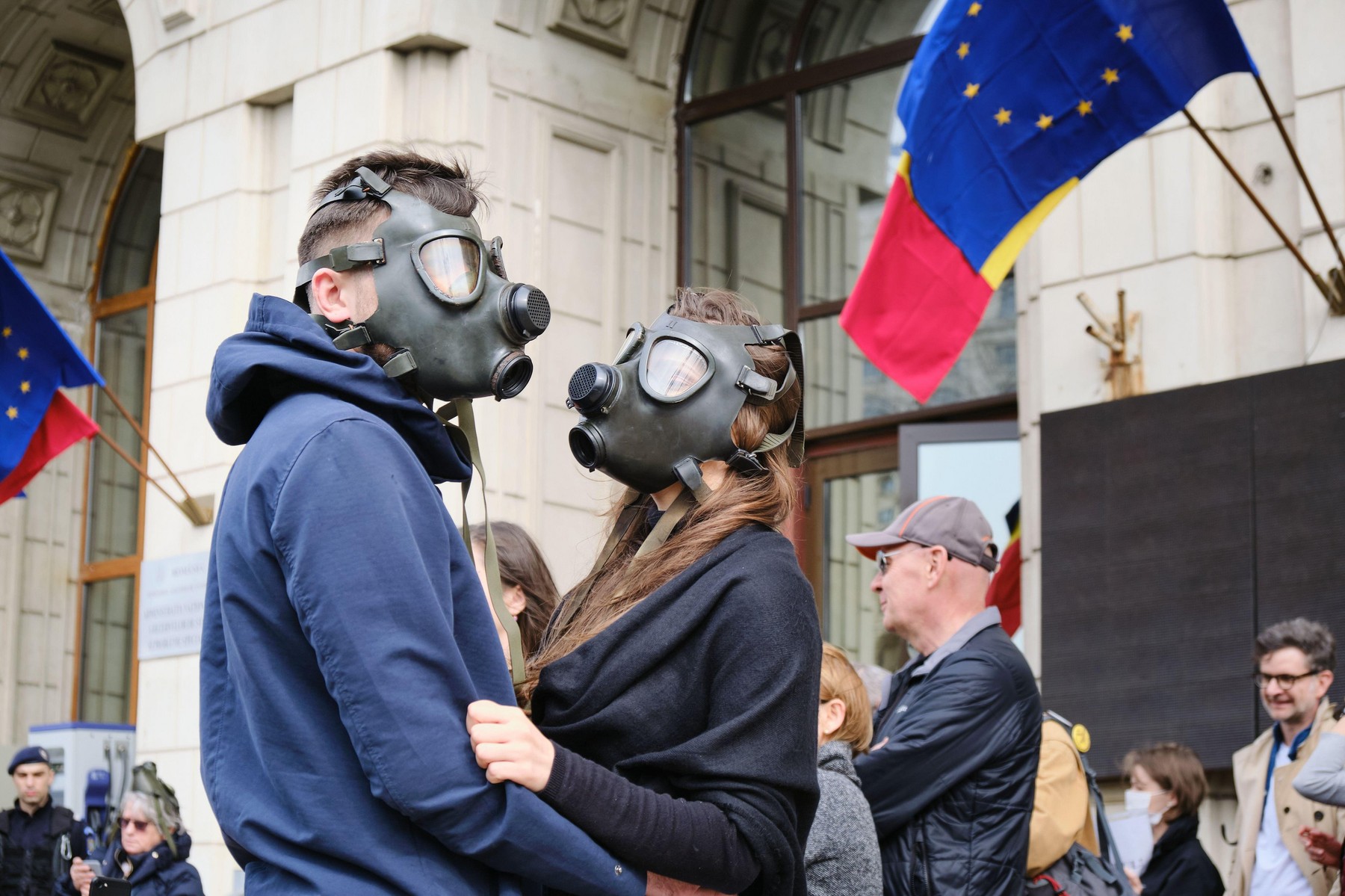 Bucharest, Romania - March 4, 2020: Couple wearing gas masks in protest for extreme air pollution, in front of the Ministry of Environment building, w