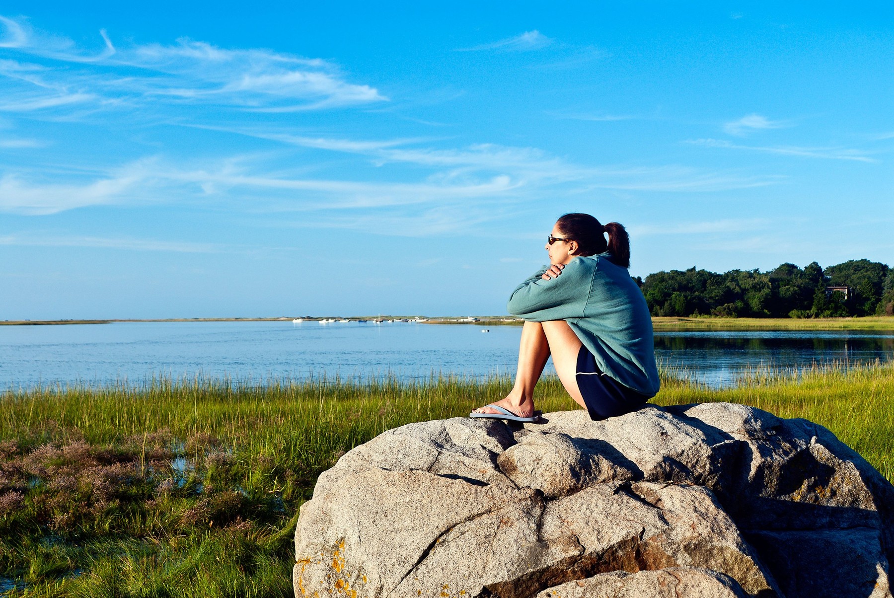 Thoughtful woman enjoying the coastal view from a boulder.