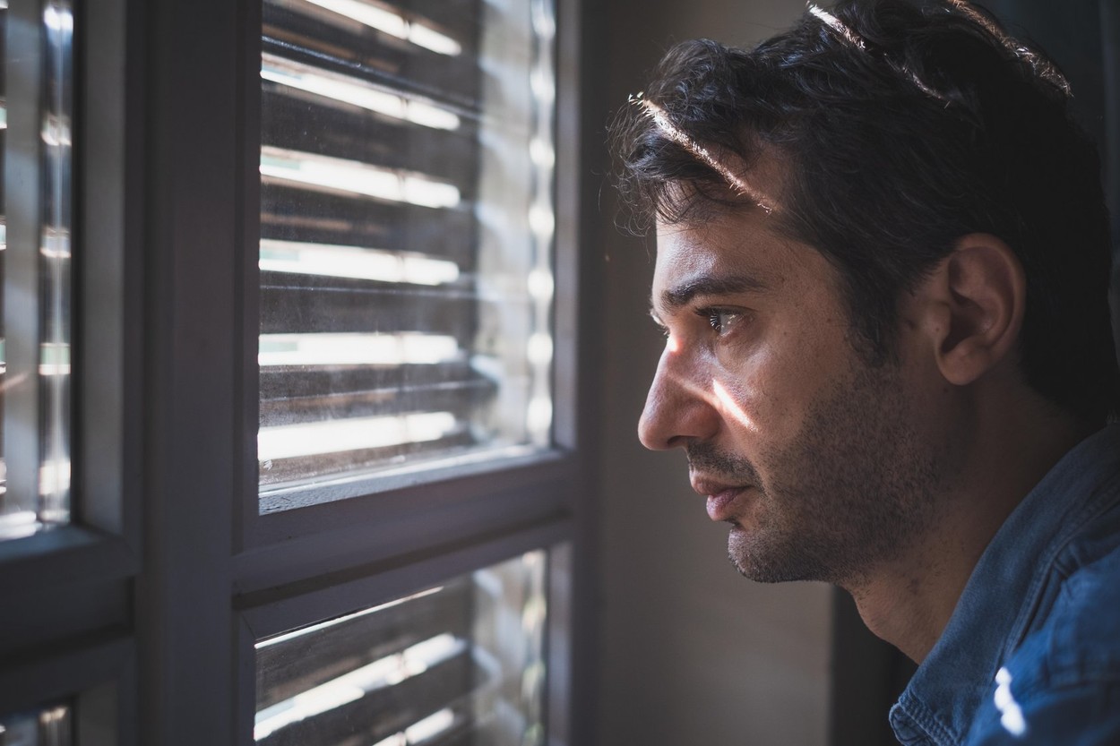 Hopeless man feeling alone and lost looking out window