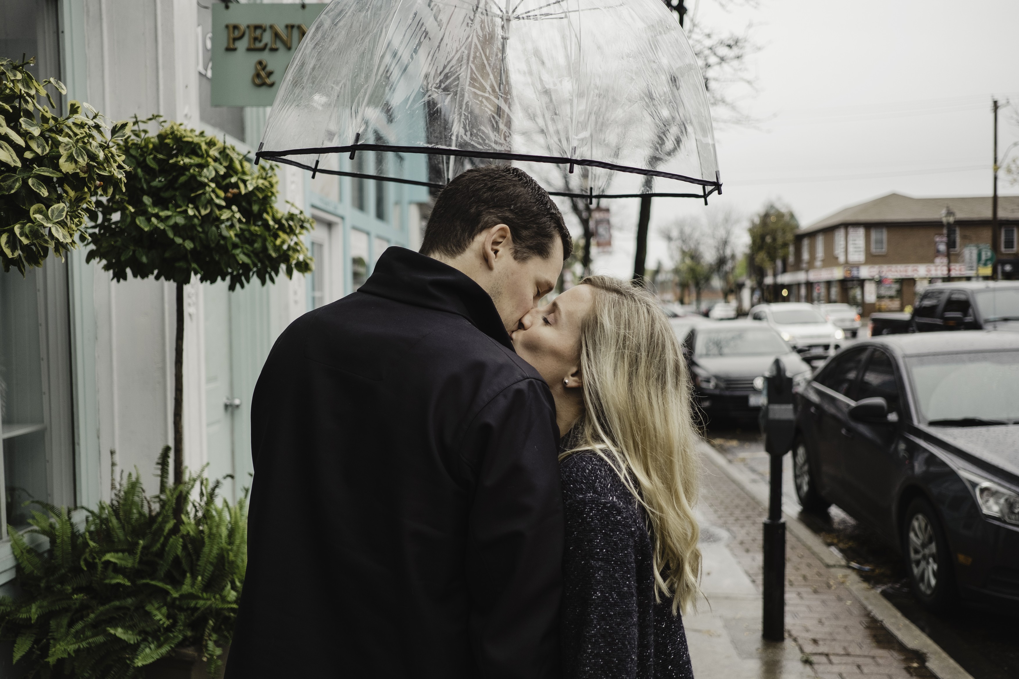 Mid adult couple in street, kissing, holding umbrella