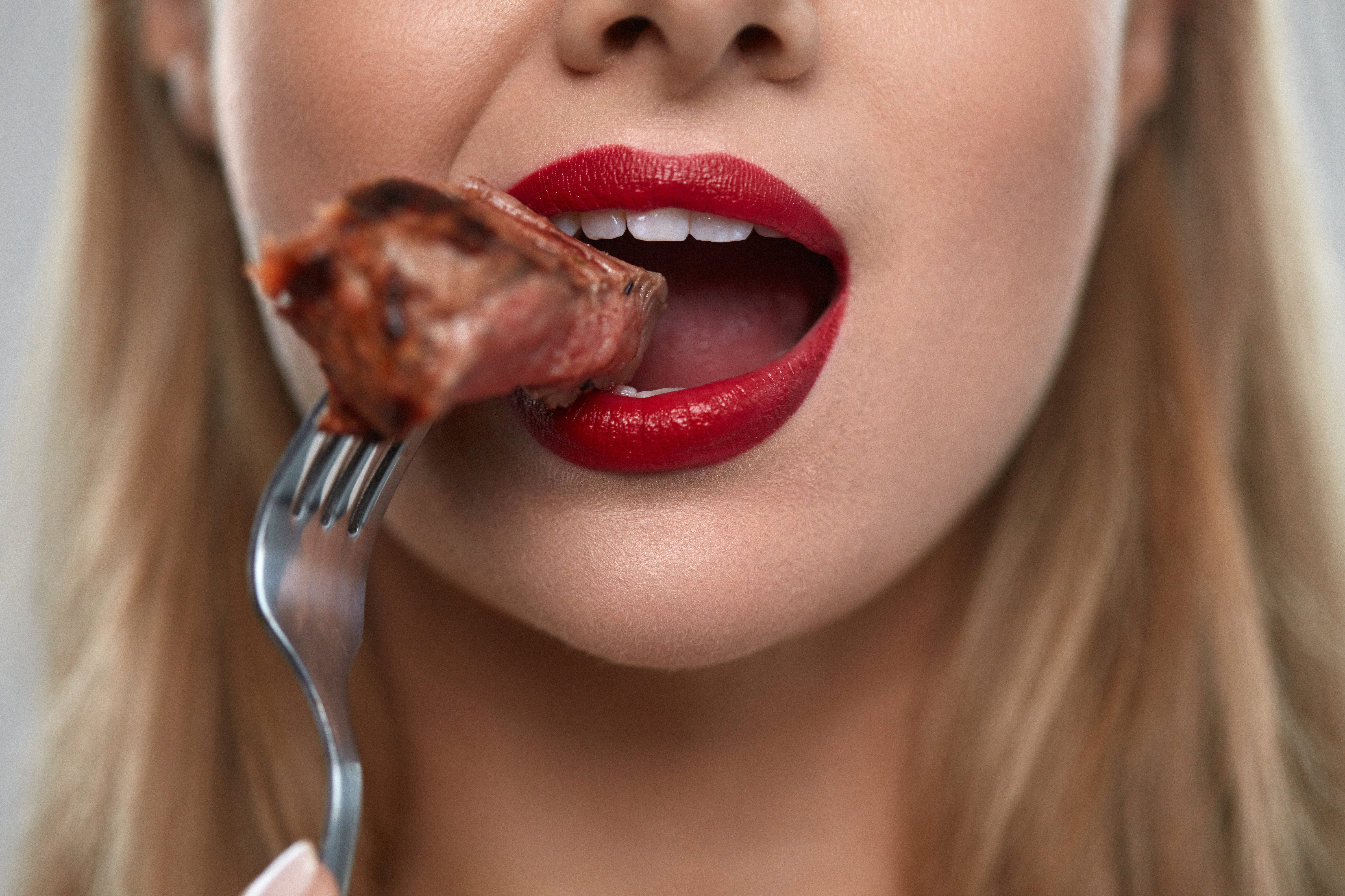 Eating,Meat.,Closeup,Of,Woman,Mouth,With,Red,Lips,,White