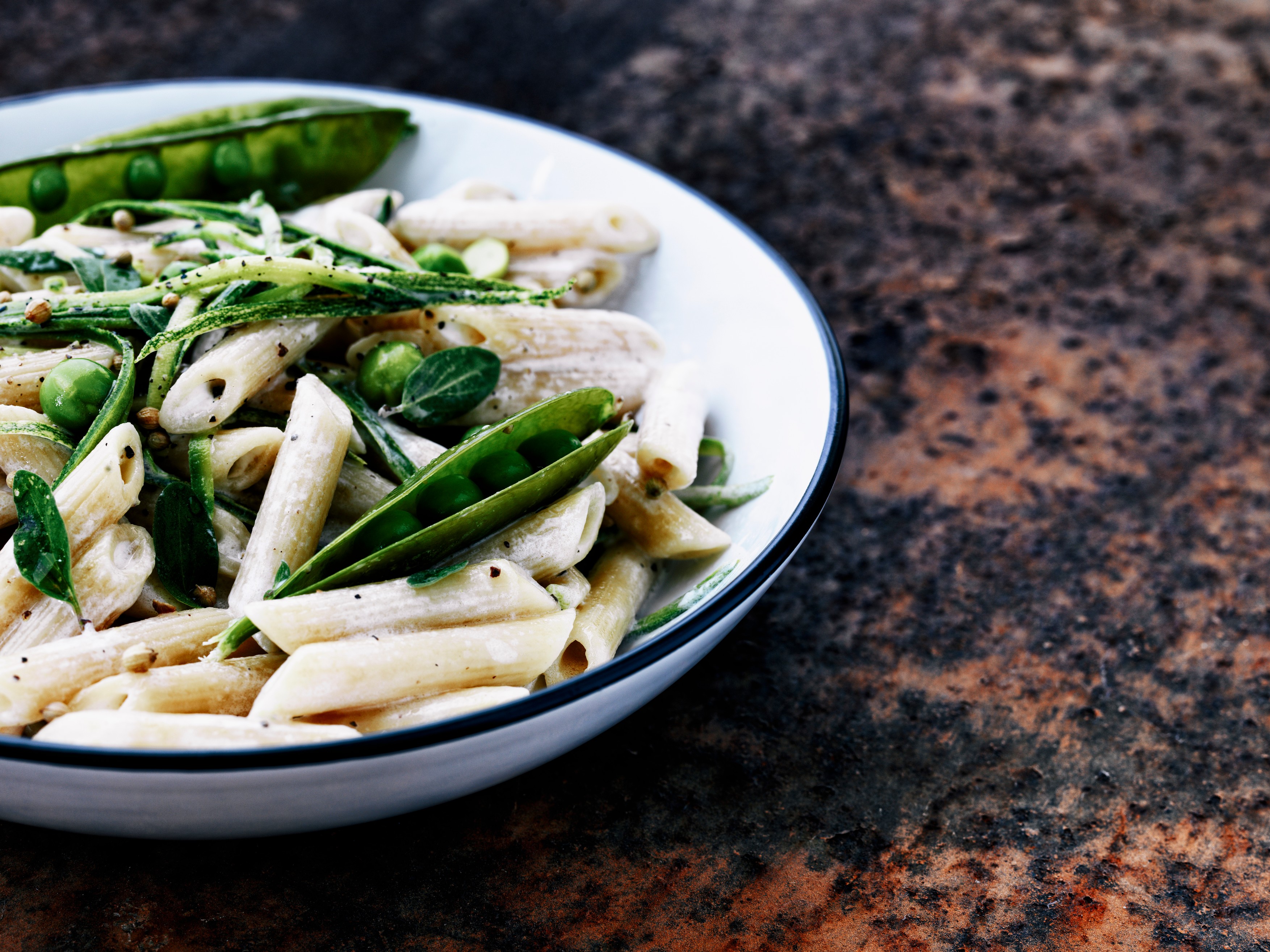 Fresh pasta in a white sauce , mixed with fresh peas in their pods