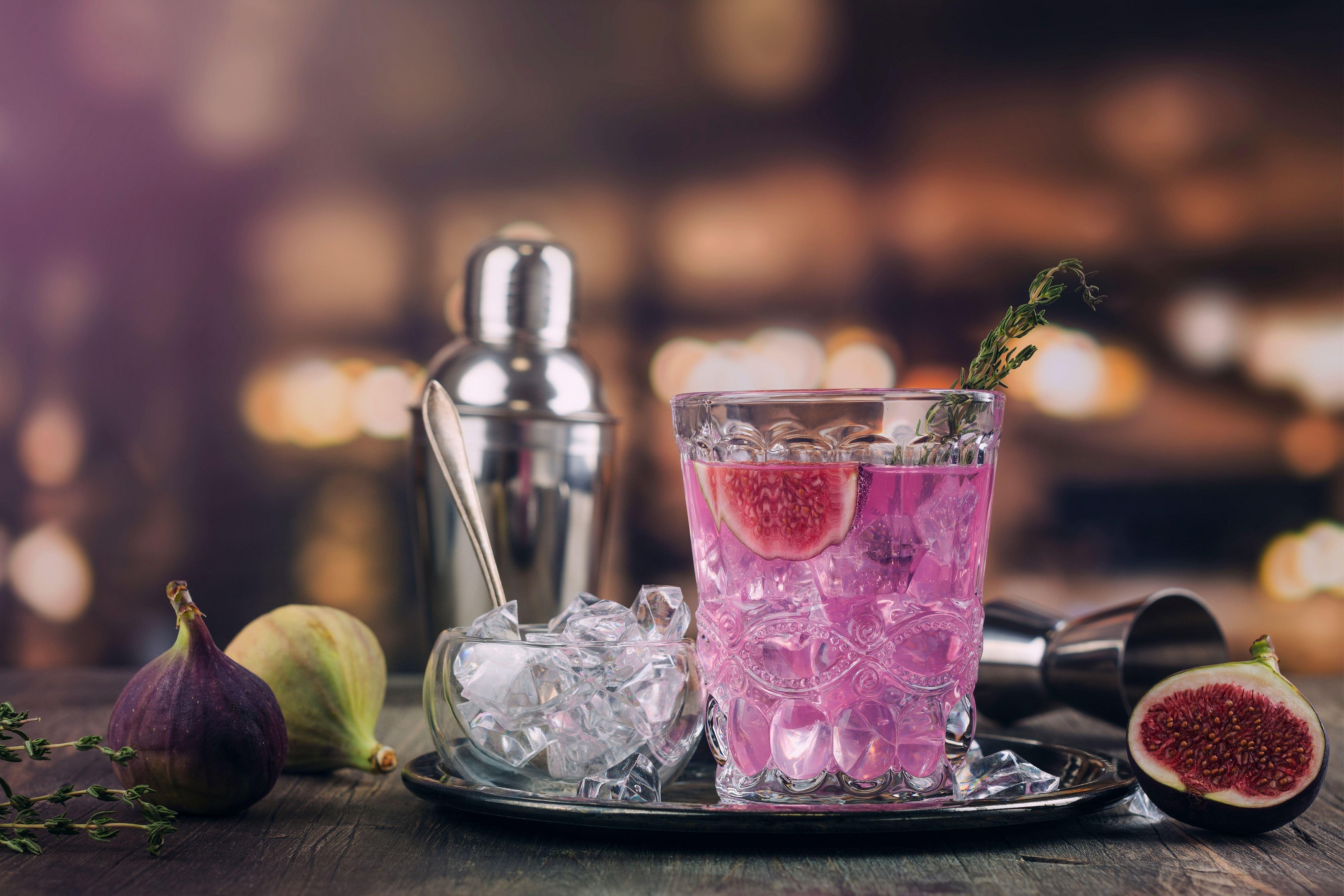 Autumn or winter pink fig cocktail in high martini glass on a bar counter. Fig cocktail with thyme and ice cubes. Selective focus