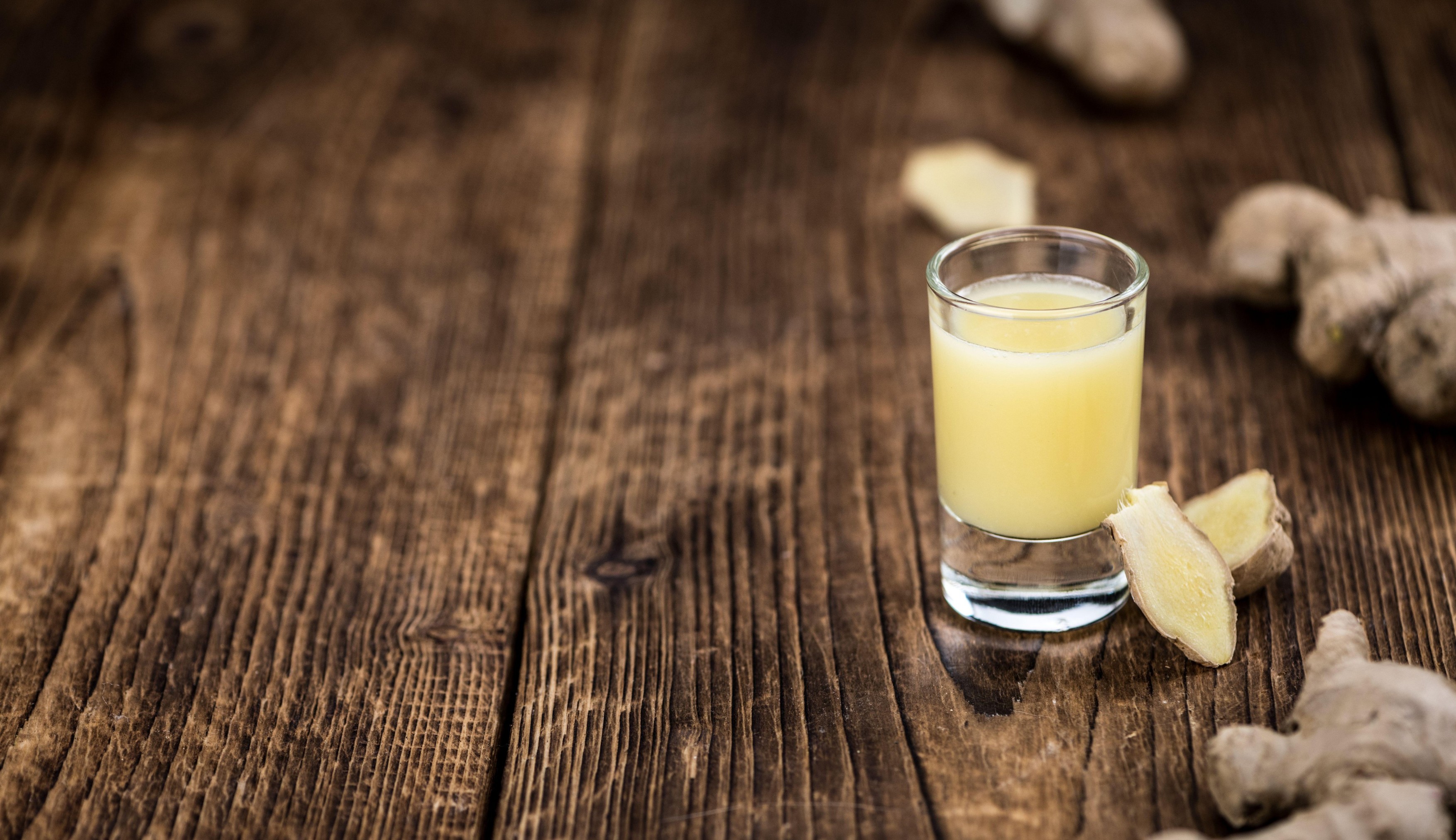 Healthy Ginger Sap on a wooden table as detailed close-up shot (selective focus)