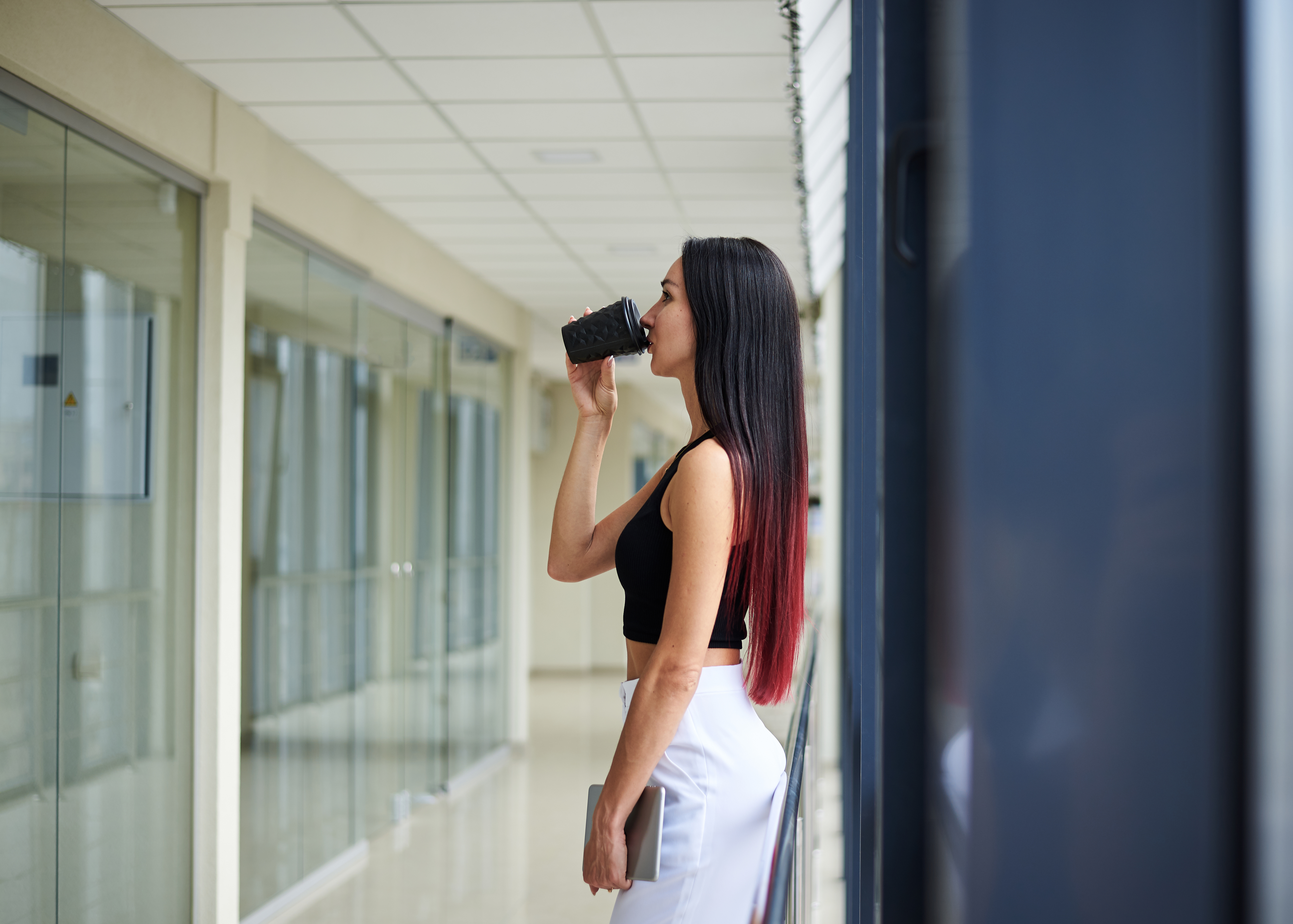 Young,Brunette,Woman,,Wearing,White,Pants,And,Black,Top,,Drinking