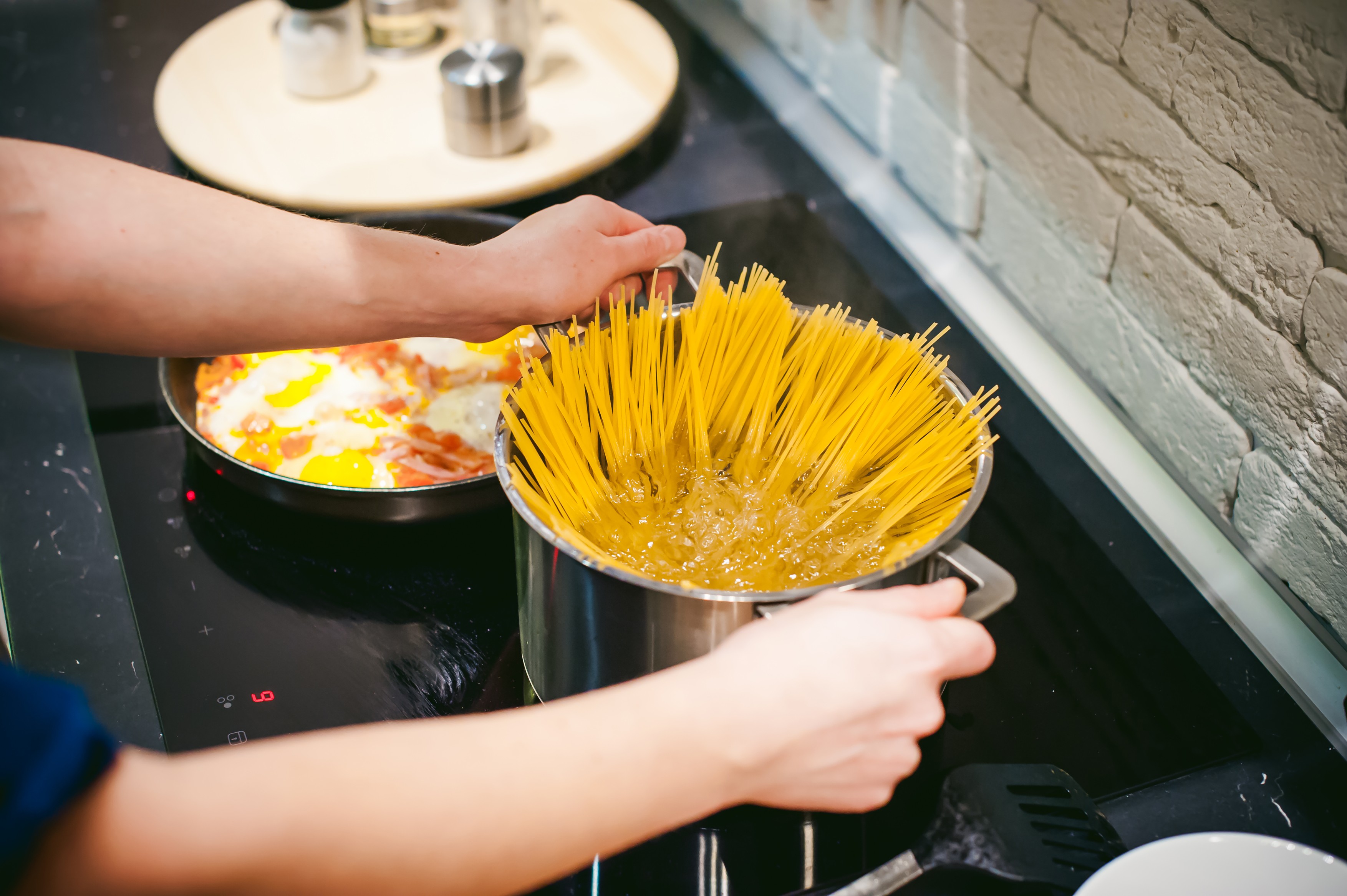 woman housewife preparing pasta in the kitchen. woman's hand dipped spaghetti in boiling water for cooking