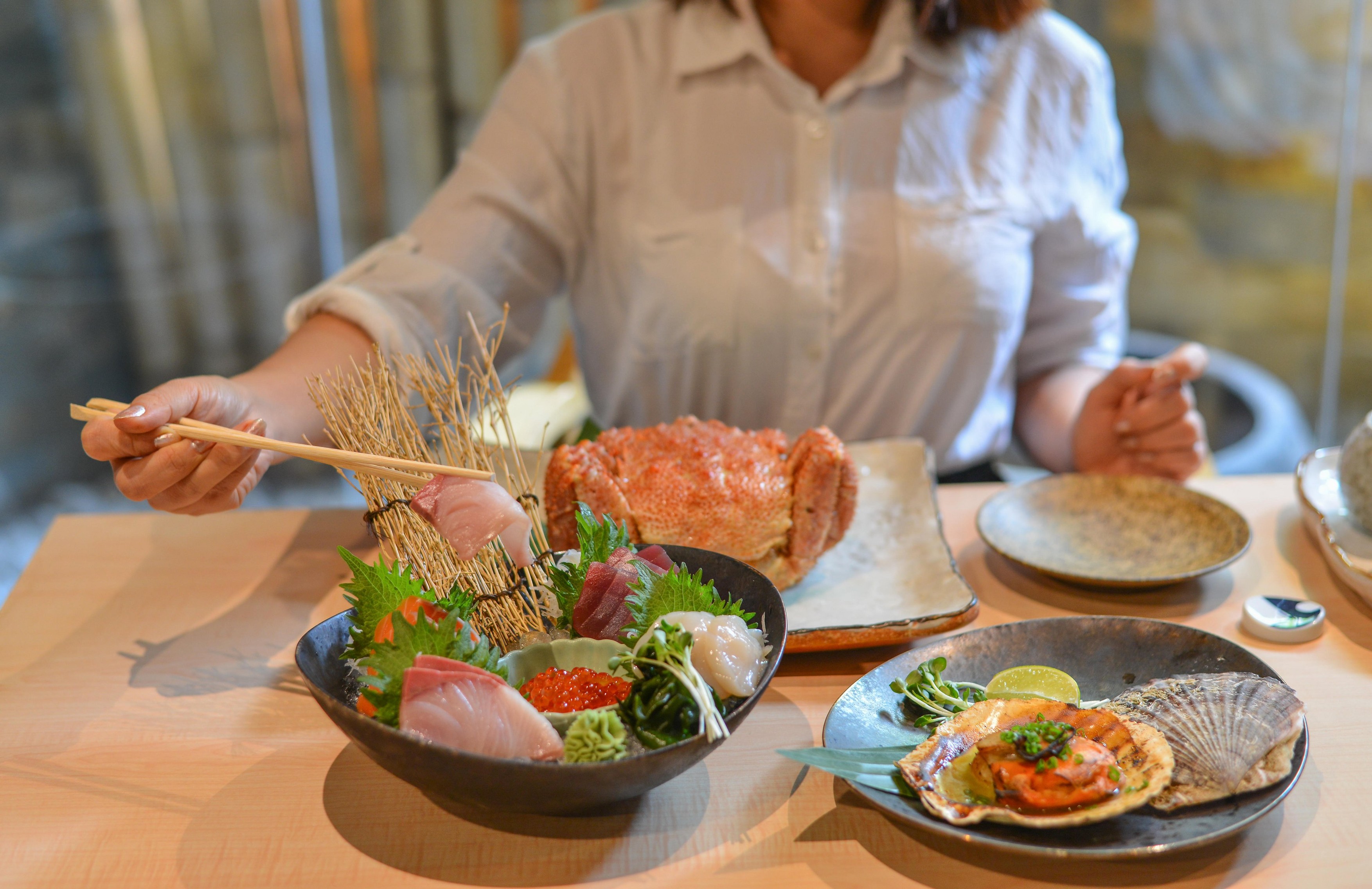 Woman eating and enjoying Japanese meal in luxury restaurant.