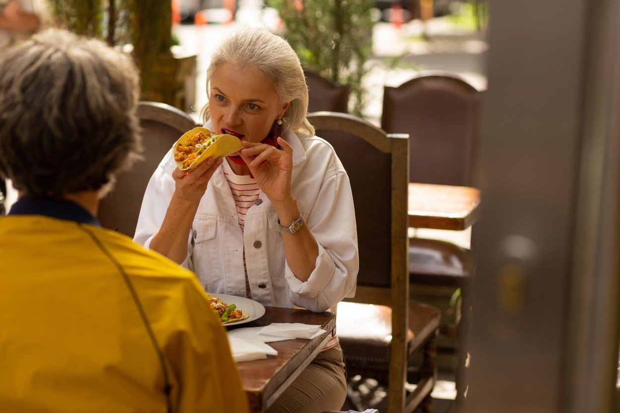 Woman eating a taco in the street cafe.