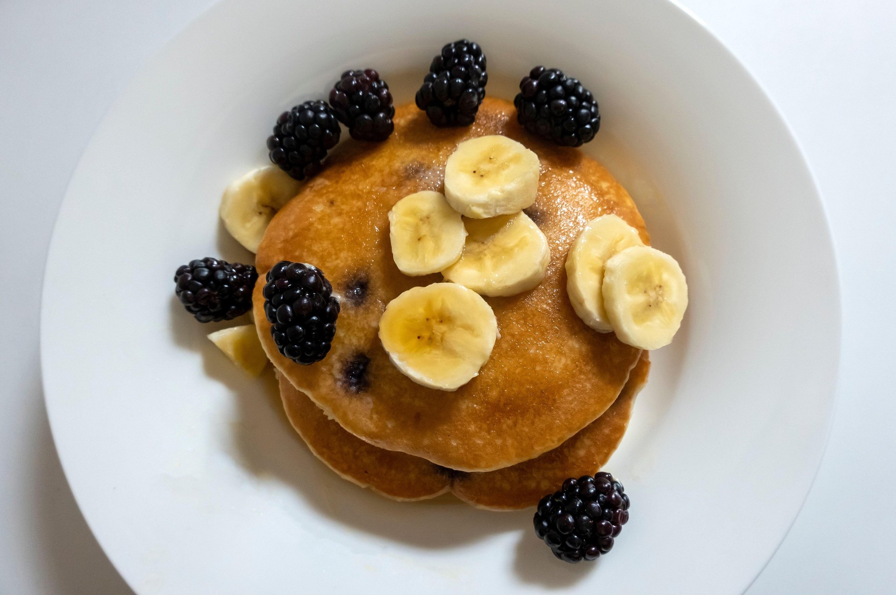 Blueberry pancakes with sliced banana and fresh blackberries