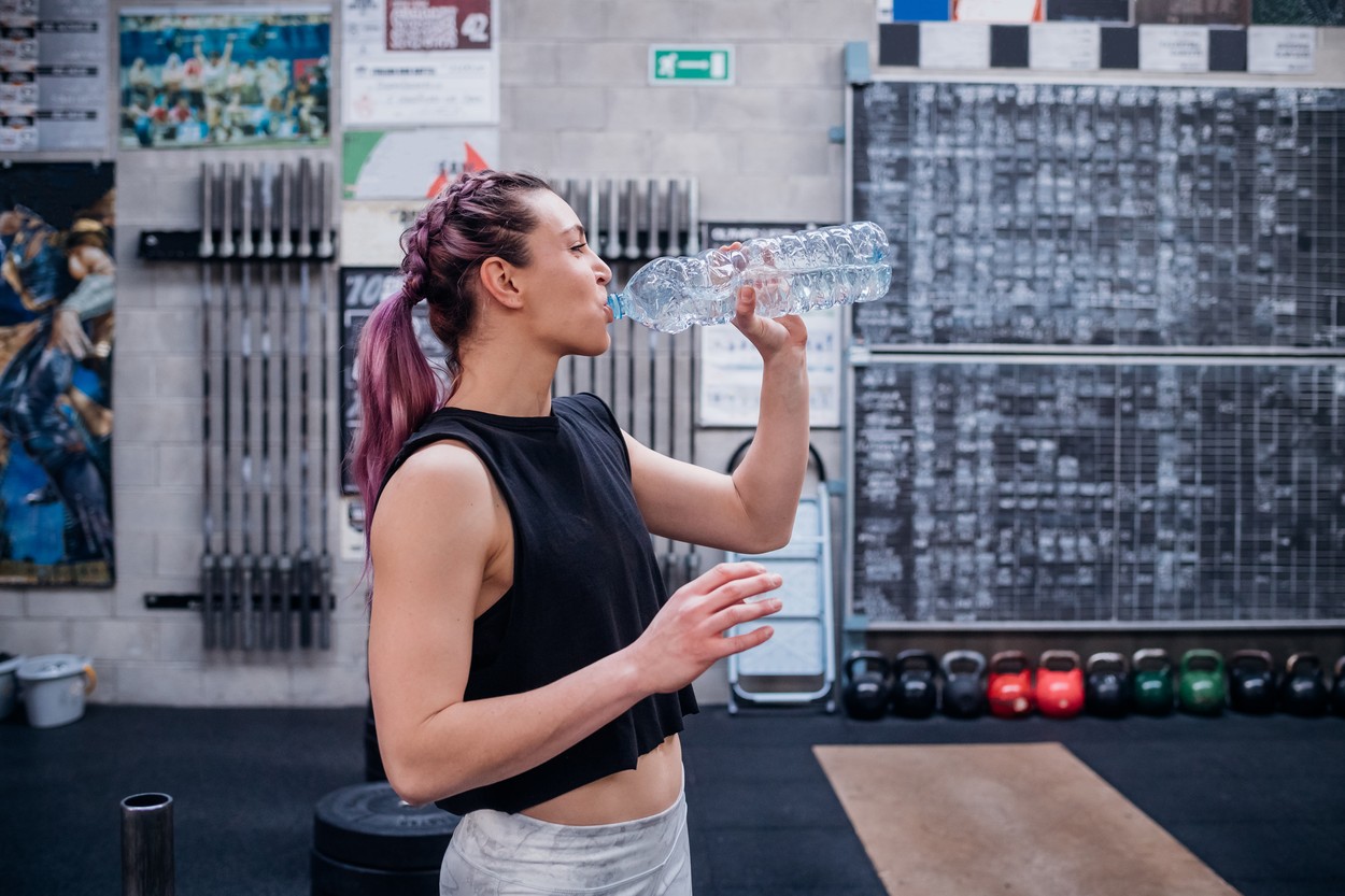 Young woman drinking water in gym