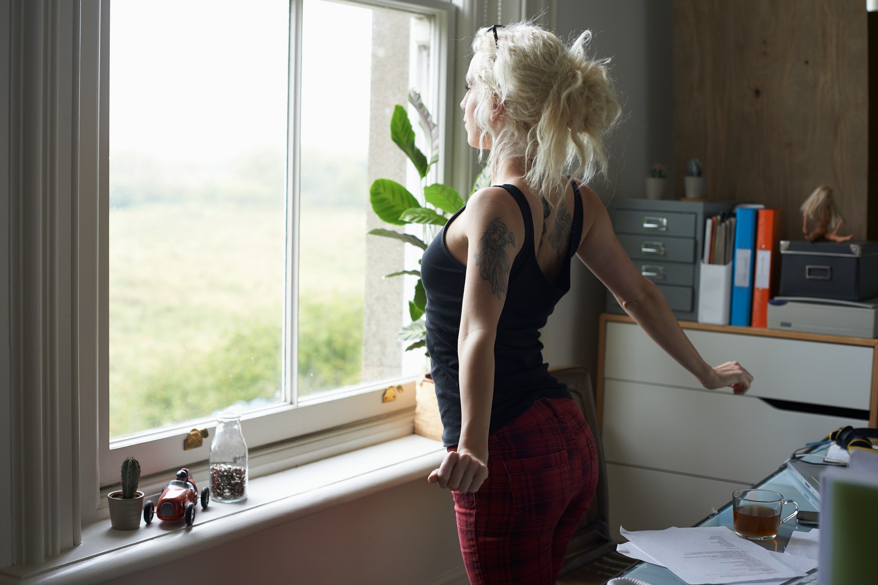 Young woman stretching at window in home office