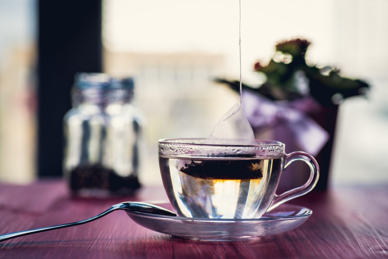 Putting tea bag into glass cup full of hot water