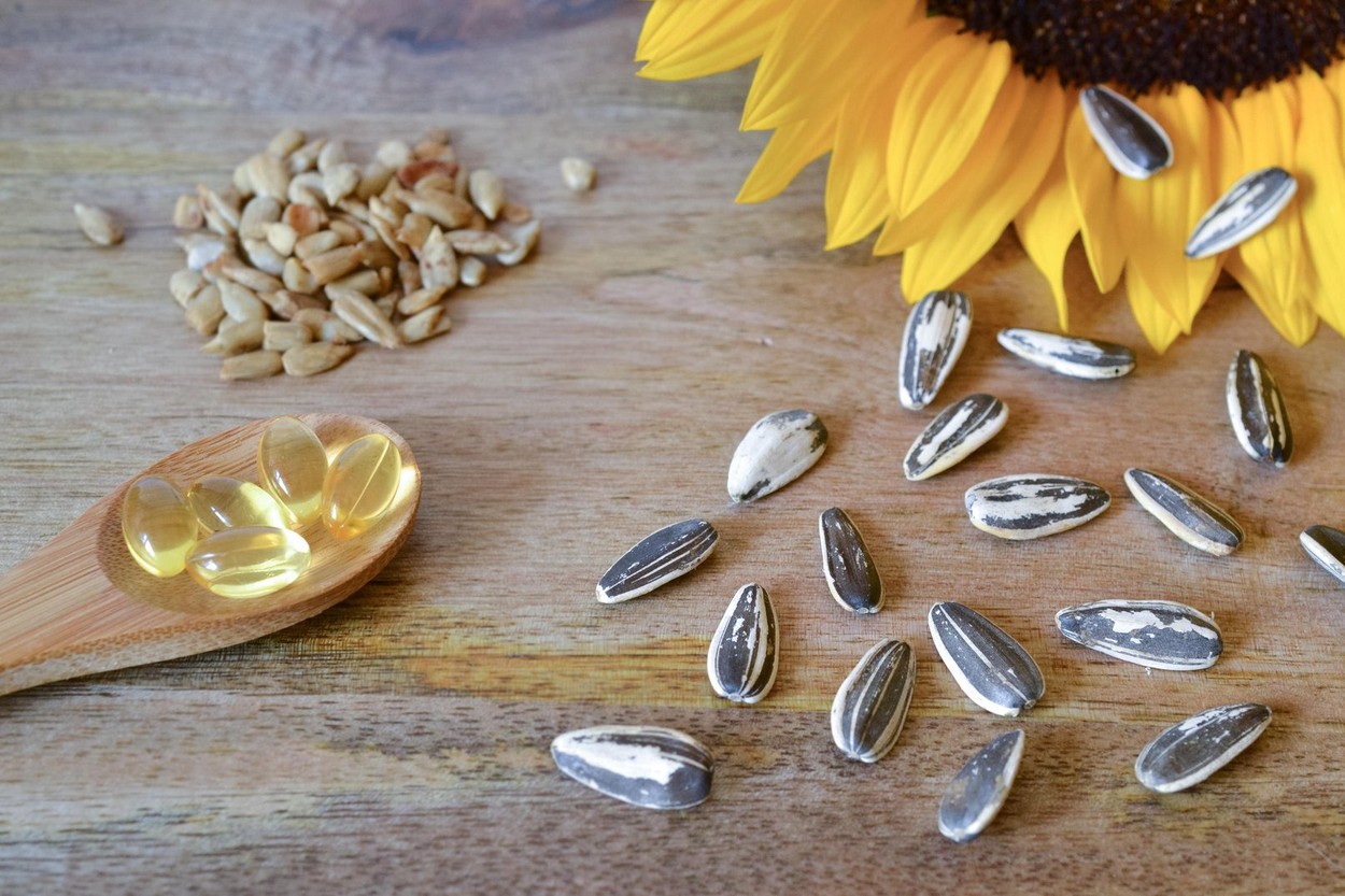 Sunflower seeds and vitamin E supplements on wooden background, decorated with a sunflower
