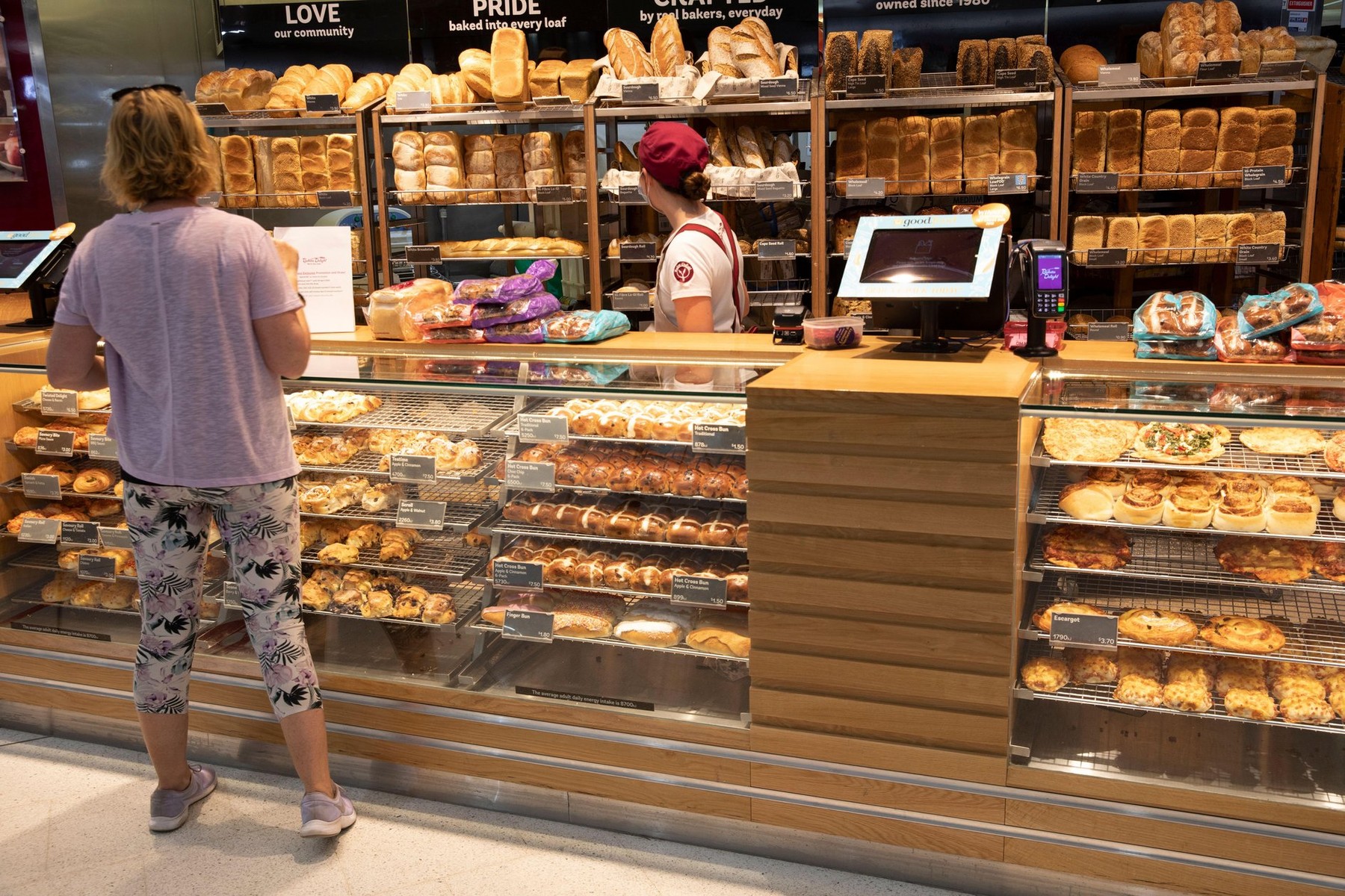 Australian lady buying bread and bread rolls from a sydney bakery during covid-19 pandemic served by asian lady wearing facemask