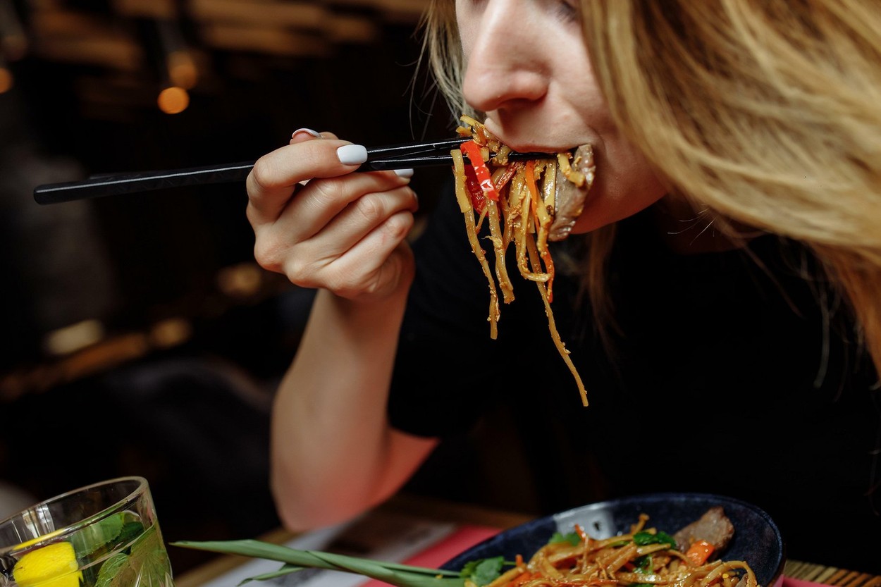Lady's hand with chopsticks. Female hand with chopsticks takes noodles and eats