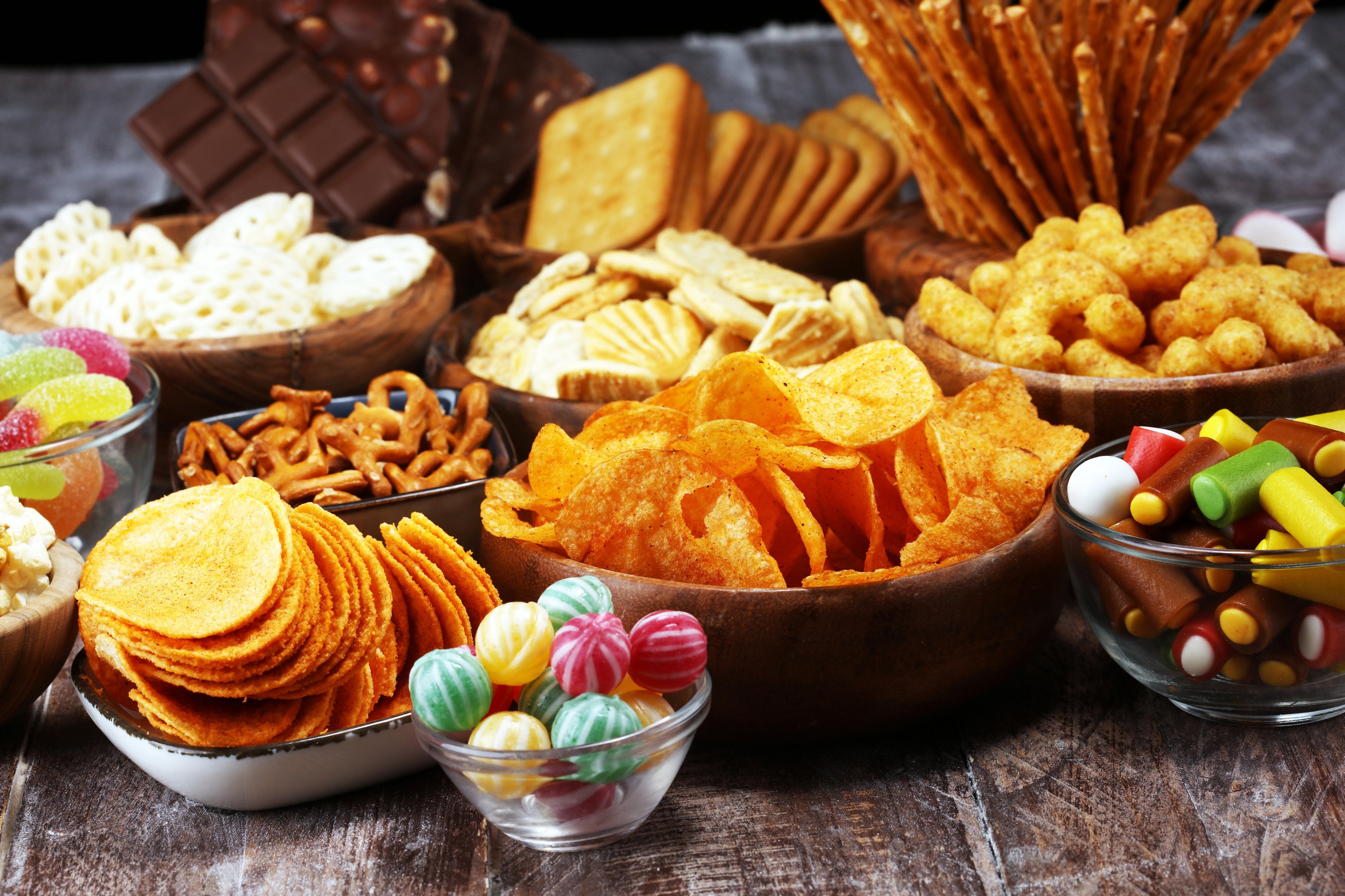 Salty snacks. Pretzels, chips, crackers in wooden bowls. Unhealthy products. food bad for figure, skin, heart and teeth. Assortment of fast carbohydra