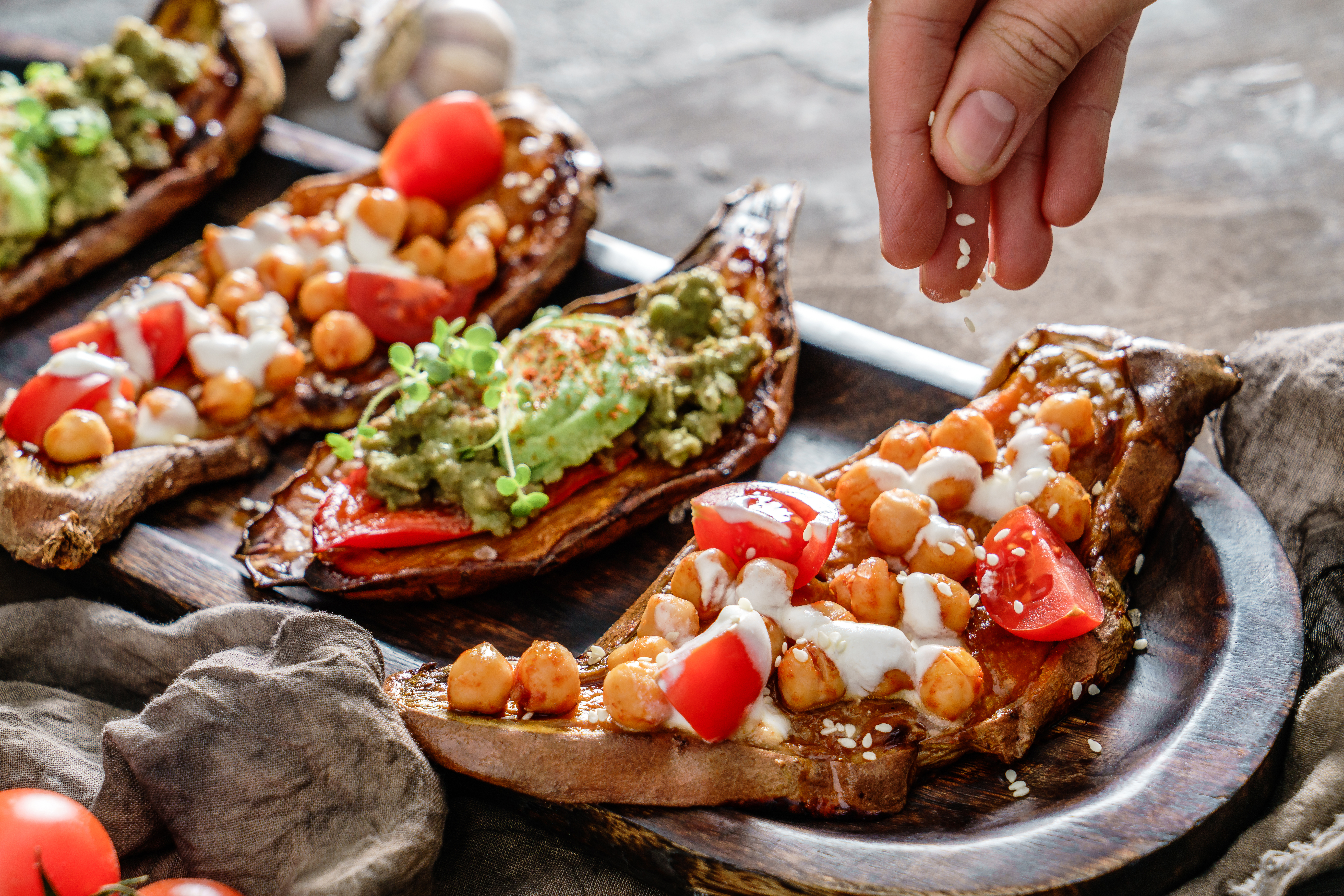 Hand,Pouring,Sesame,Seeds,On,Baked,Sweet,Potato,Toasts,With