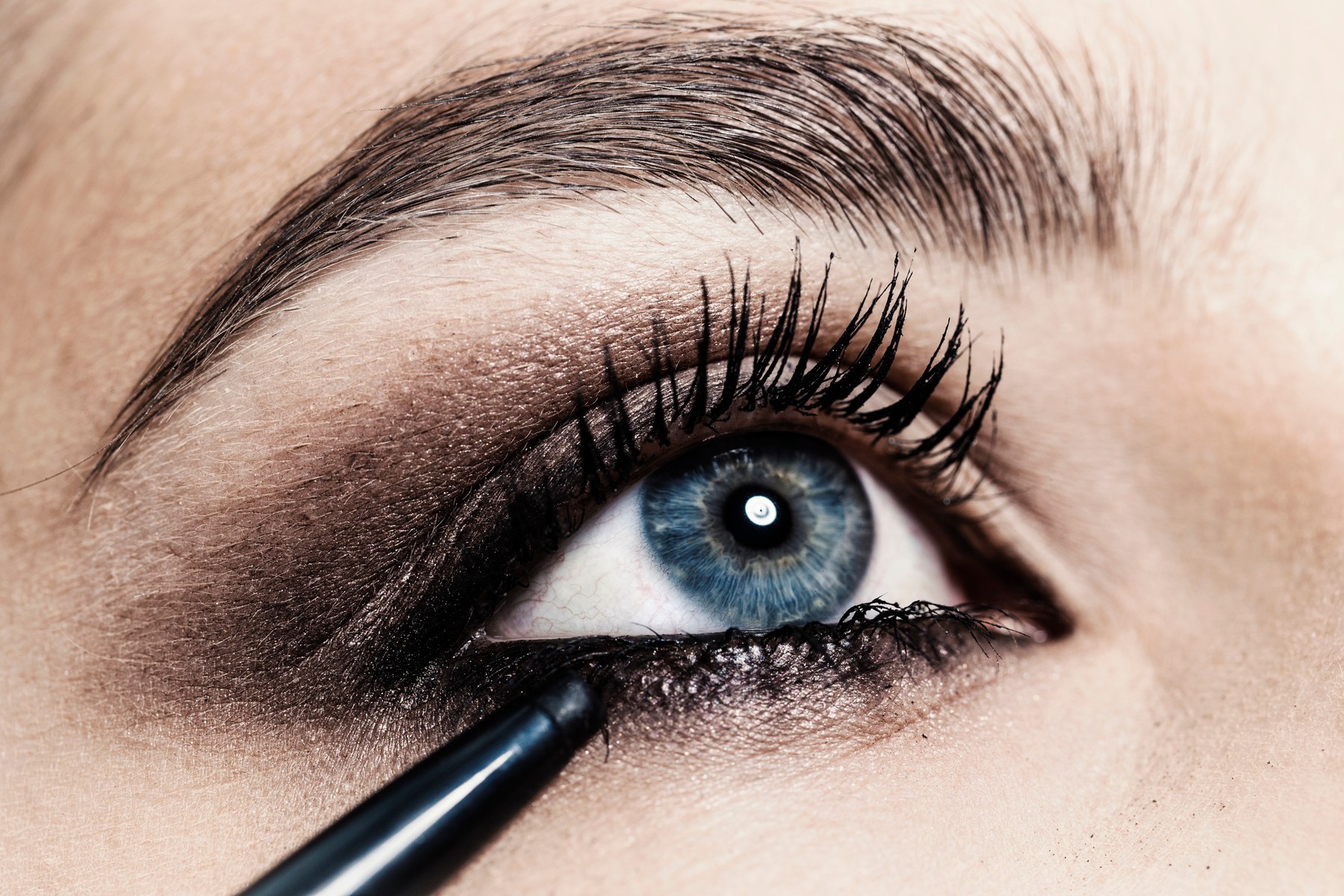 Close up of eyeliner being applied to young woman's eye