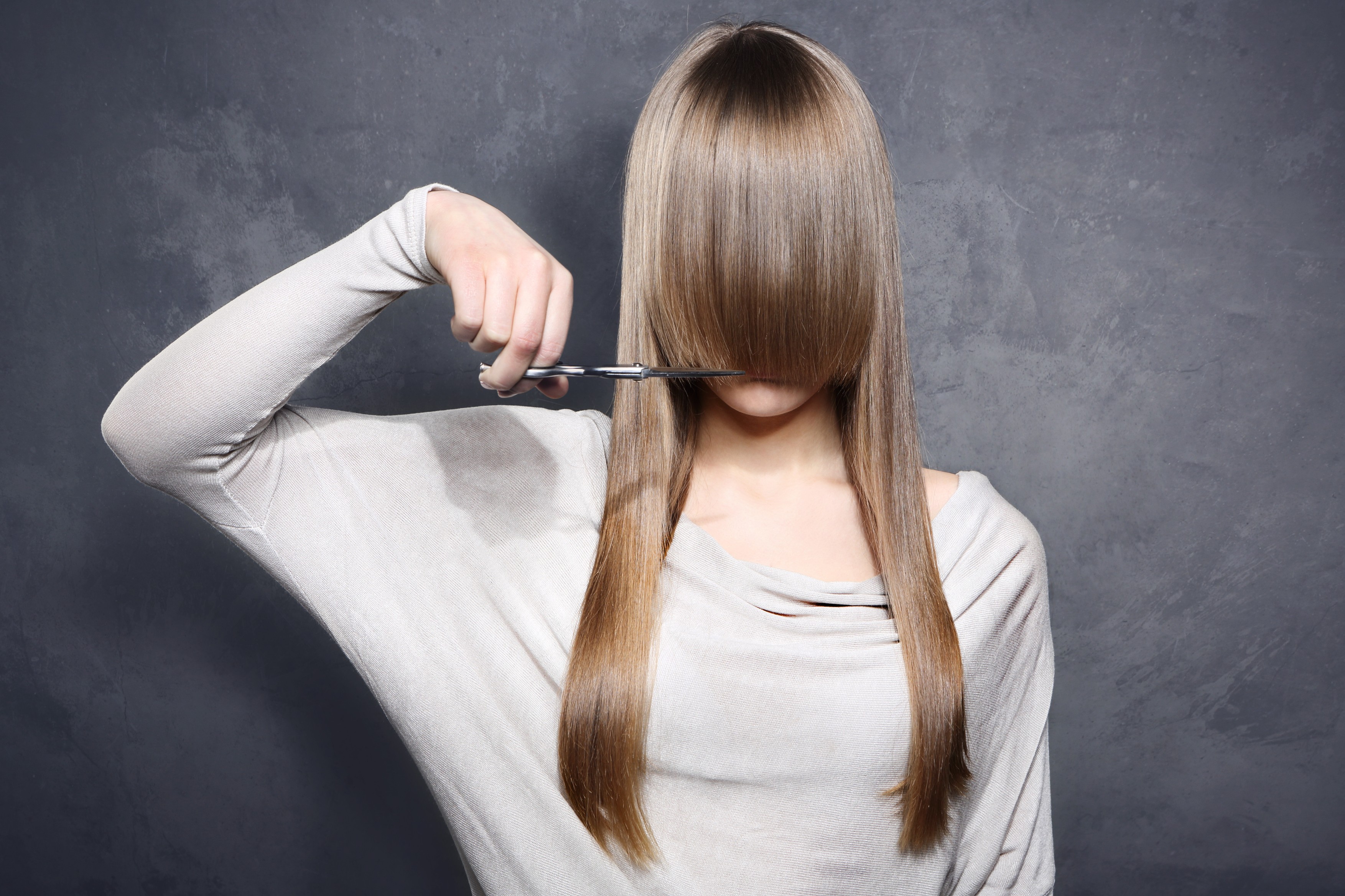 woman with scissors cut her bangs.